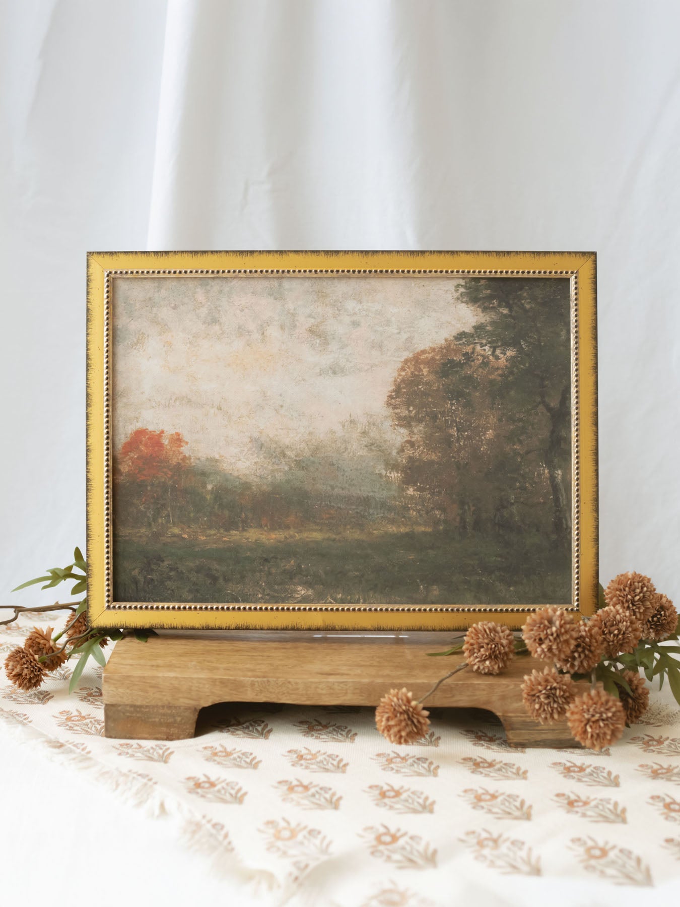 A richly atmospheric landscape featuring an open meadow framed by trees dressed in warm autumn hues. Soft light, layered textures, and painterly brushwork evoke the peaceful beauty and quiet elegance of the changing seasons.