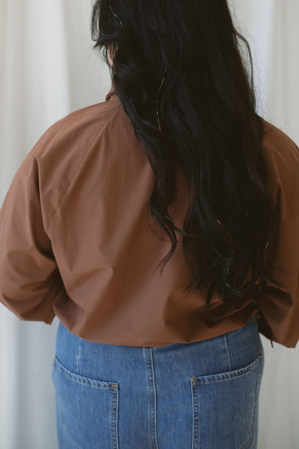 Woman wearing the half zip active jacket in cocoa with medium wash denim and standing in front of a white background