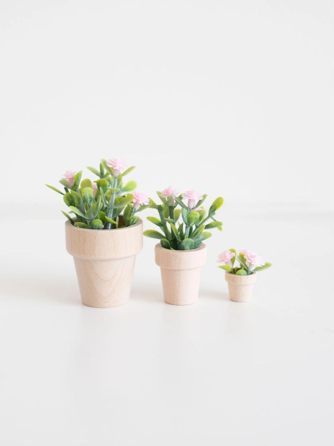 three sizes of dollhouse pink flower potted plants on a white background