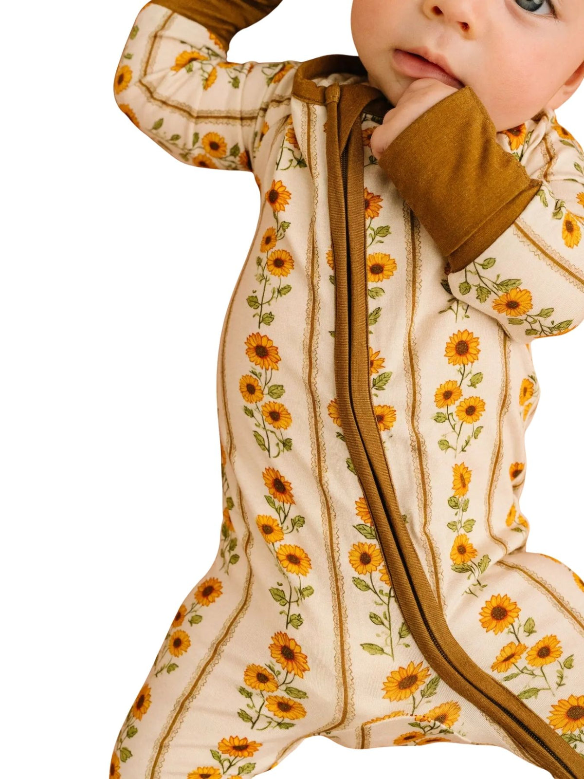 close up picture of a baby wearing a sunflower and stripe zip sleeper on white background