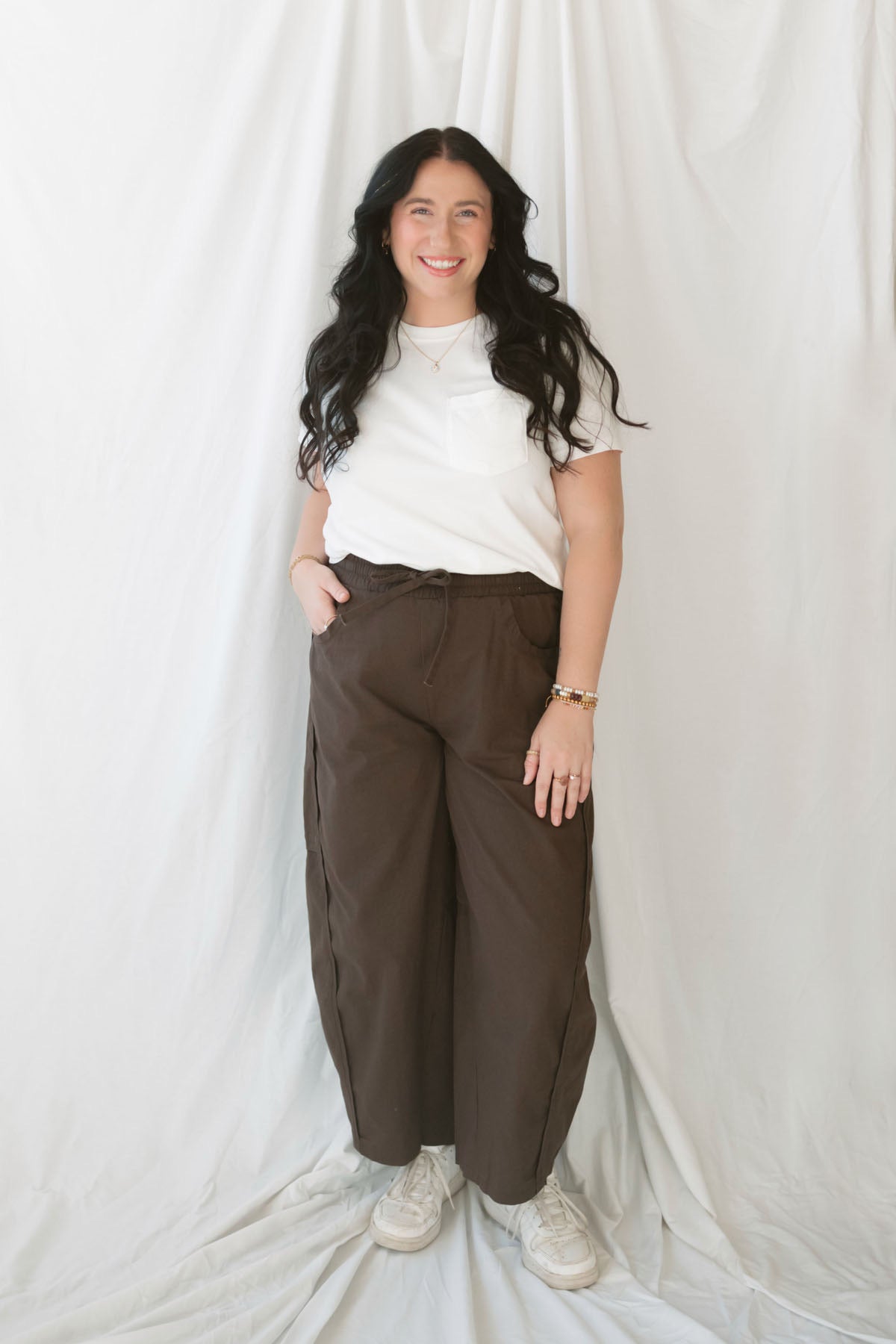 Model wearing basic white crew neck tee with pocket detail.