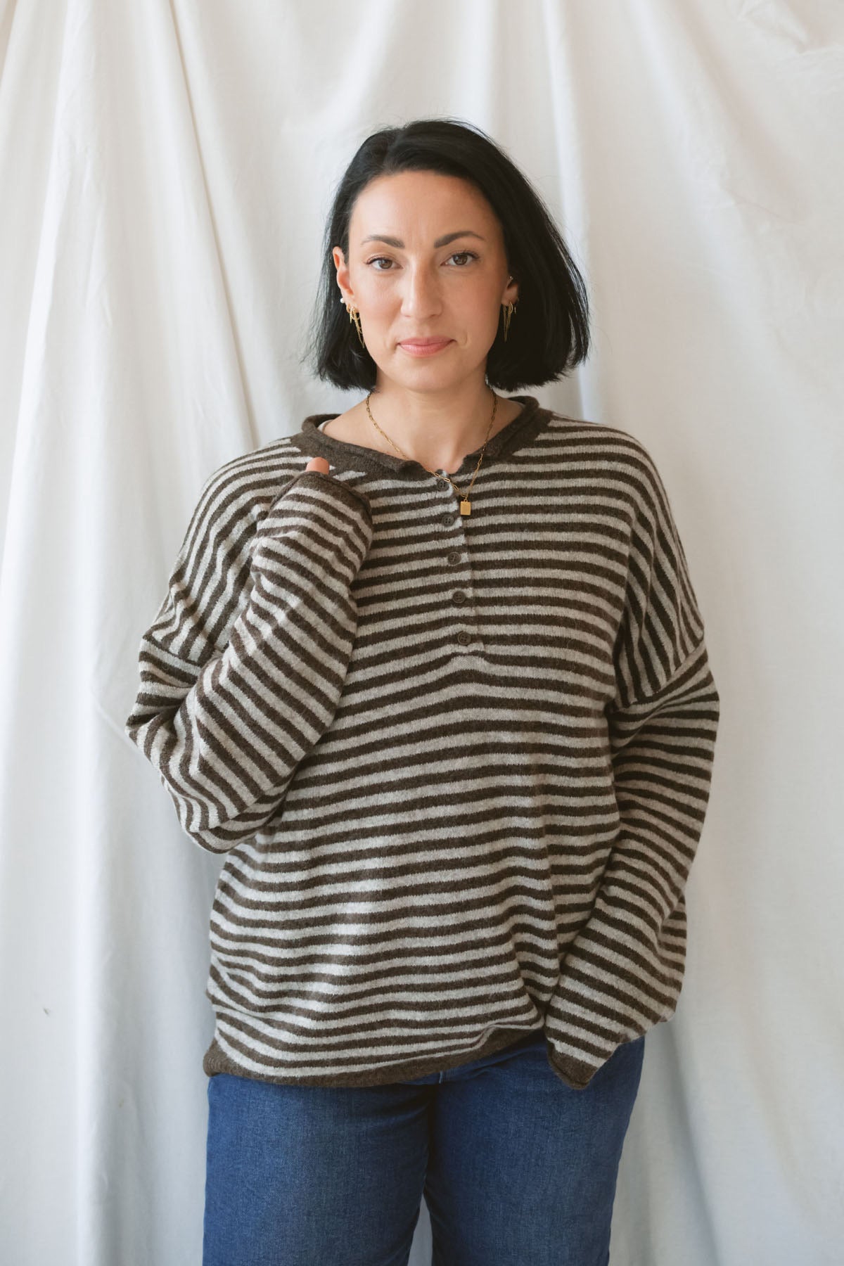 Model wearing a deep brown and tan henley button sweater.