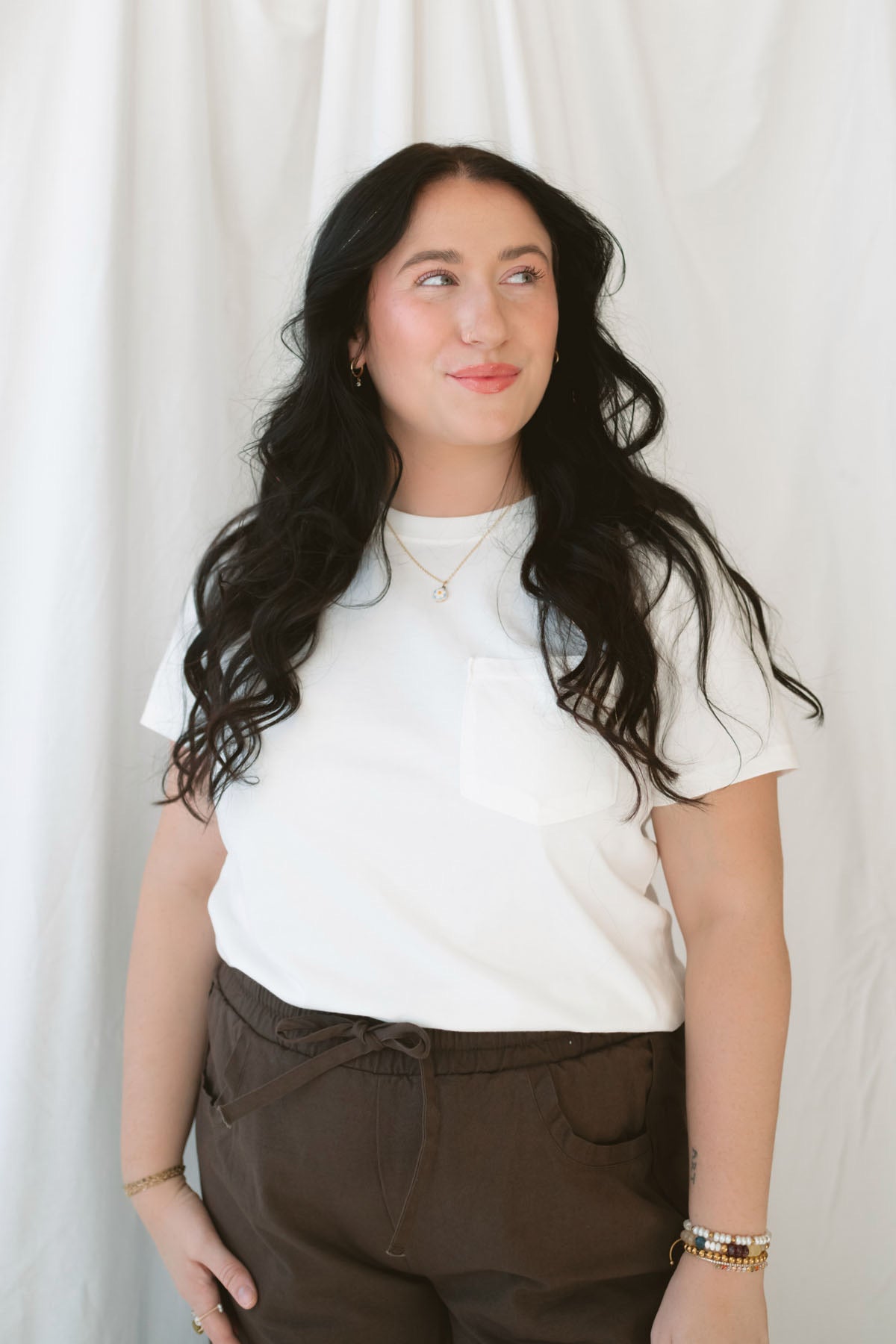 Model wearing basic white crew neck tee with pocket detail.