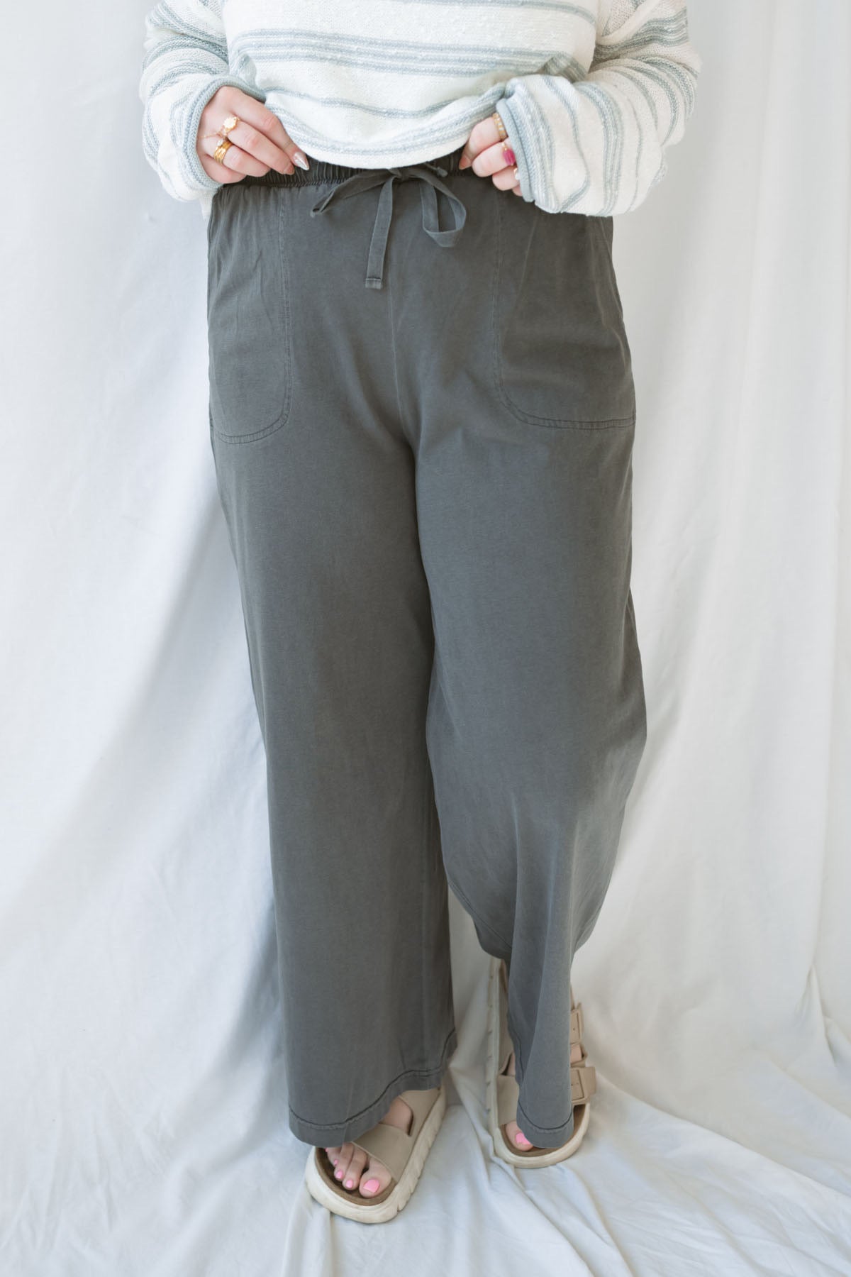 Model wearing cotton wide leg pants with drawstring waistband. Model has the pants styled with a lightweight sweater, but they can be paired with other basics tees or blouses.