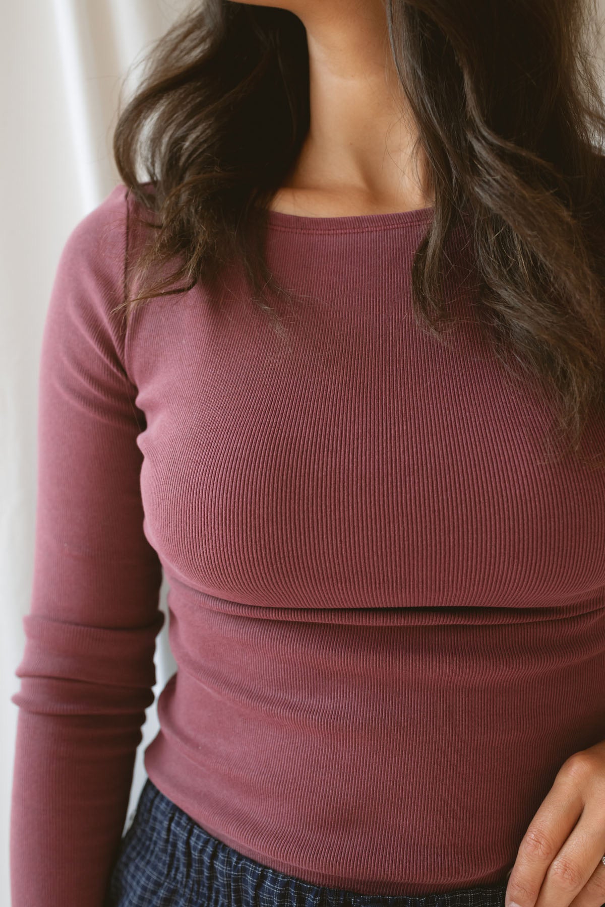 Model wearing ribbed long sleeve top with boat style neckline. Model has top styled with our navy checkered wide leg pants, but could be paired with a variety of bottoms.