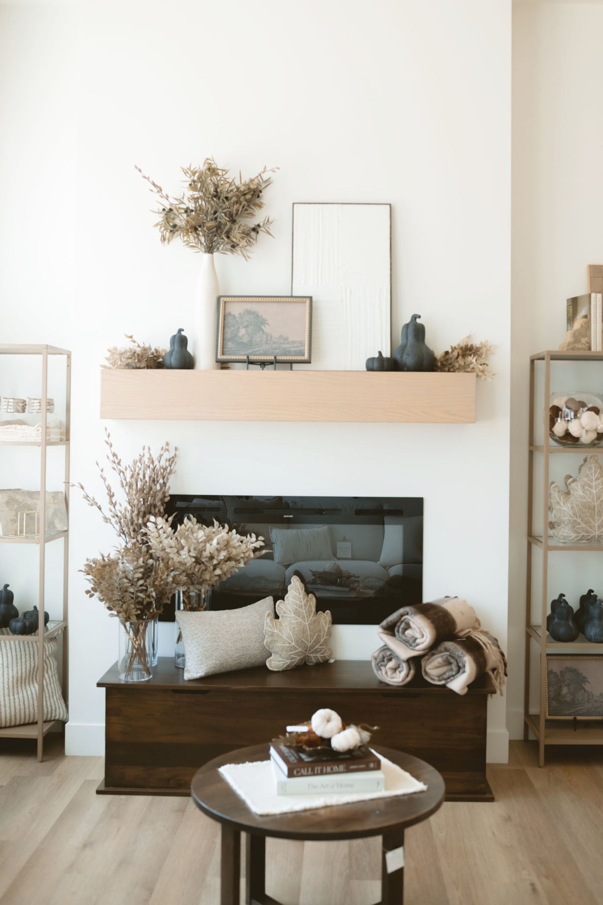 Brown thistle stem styled on mantel with art work and black terracotta gourds.