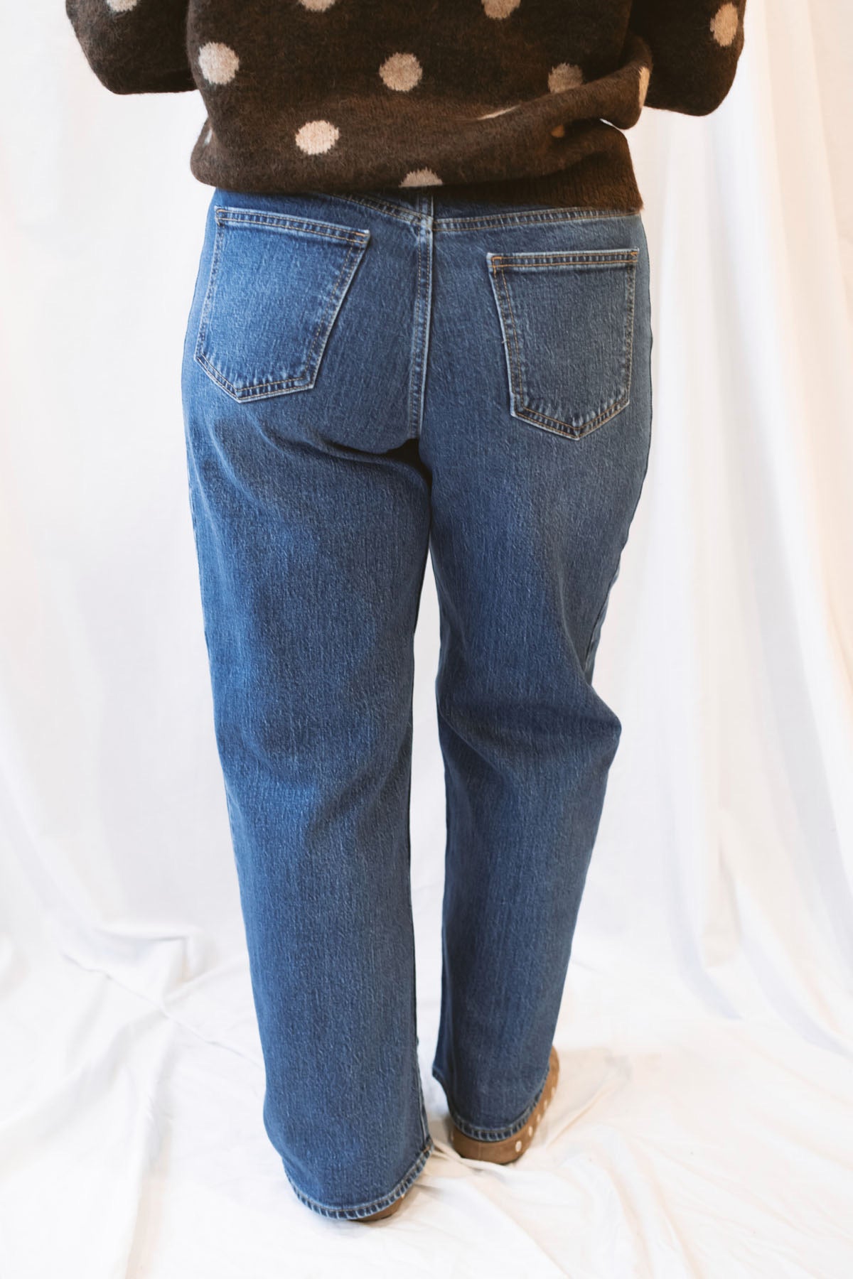 Dark wash stretch barrel-leg jeans for women featuring a subtle curved leg silhouette, twisted seam detailing, and a modern relaxed denim design.