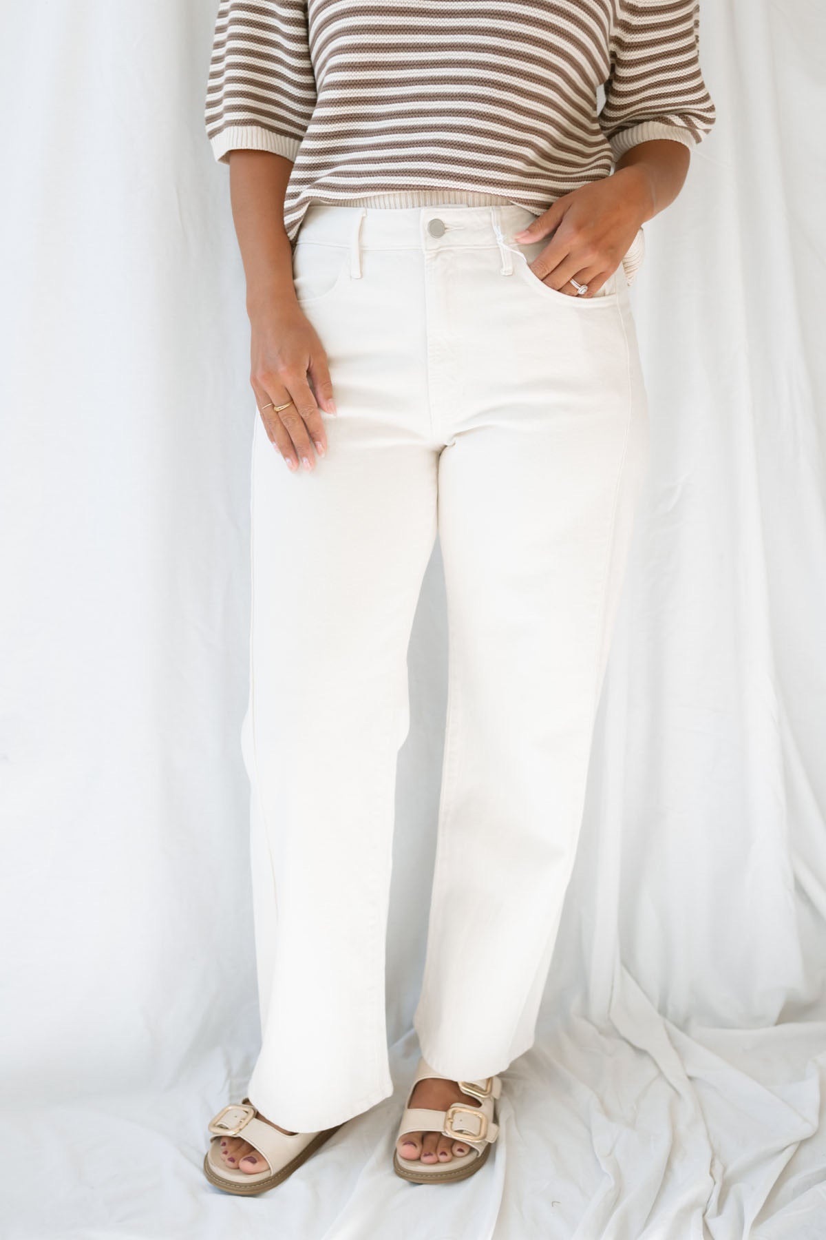 Model wearing the high rise stretch barrel denim pants in off white.