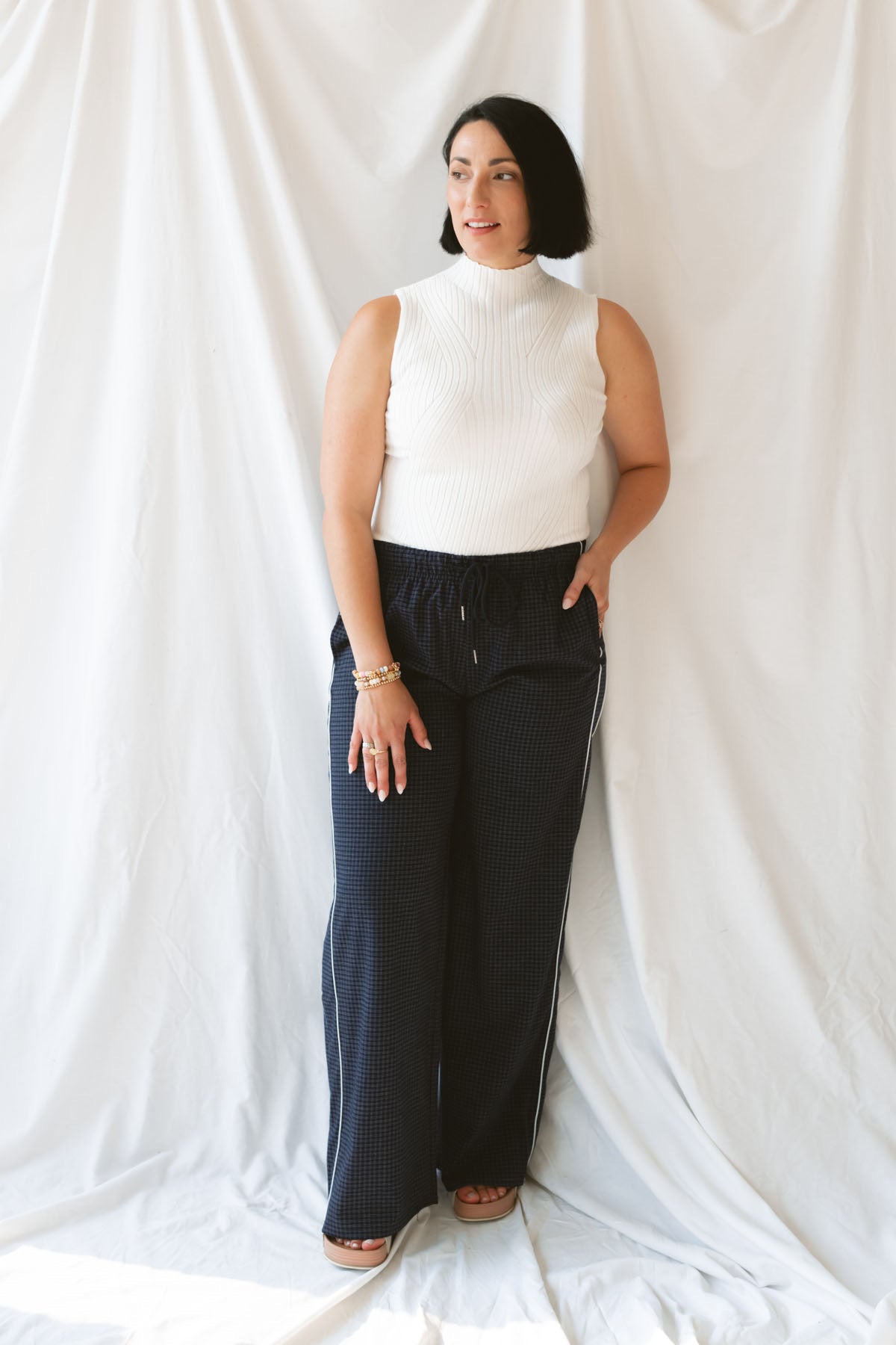 Model wearing the ribbed sleeveless high neck top in off white. A staple for your wardrobe from season to season.