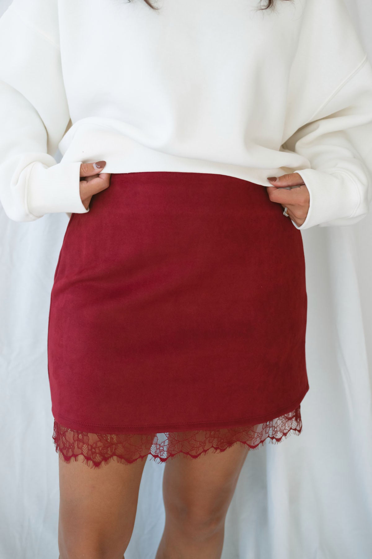 Model wearing suede mini skirt with lace trim detail.