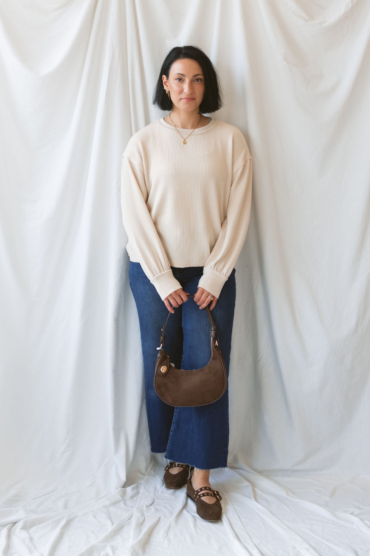 Model wearing a textured exposed seam long sleeve top in a natural color.