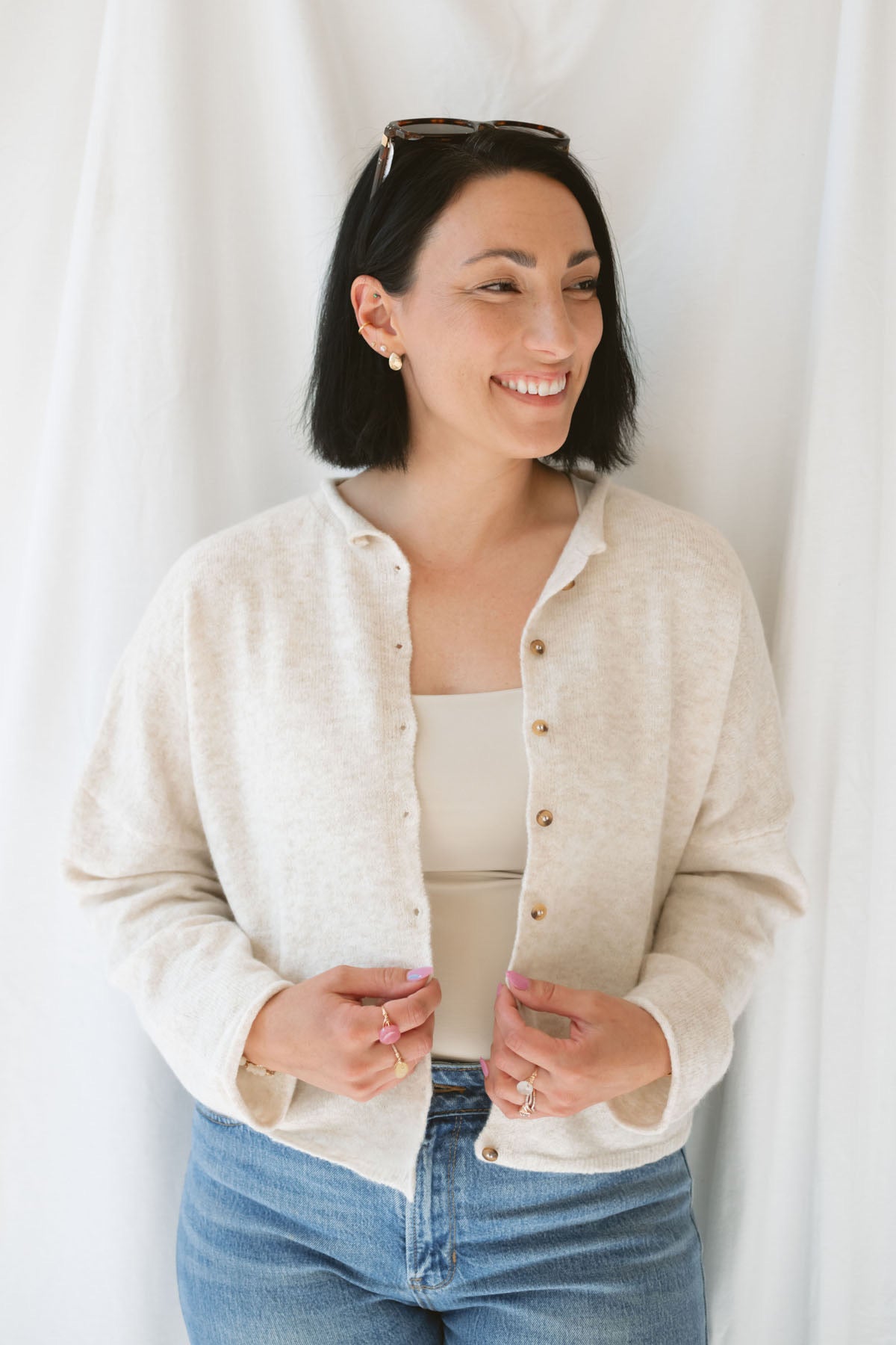 Model wearing button up cardigan in color oat. This cardigan is easy to wear open and layered over a variety of tanks and shirts or you can wear it buttoned up as a top.