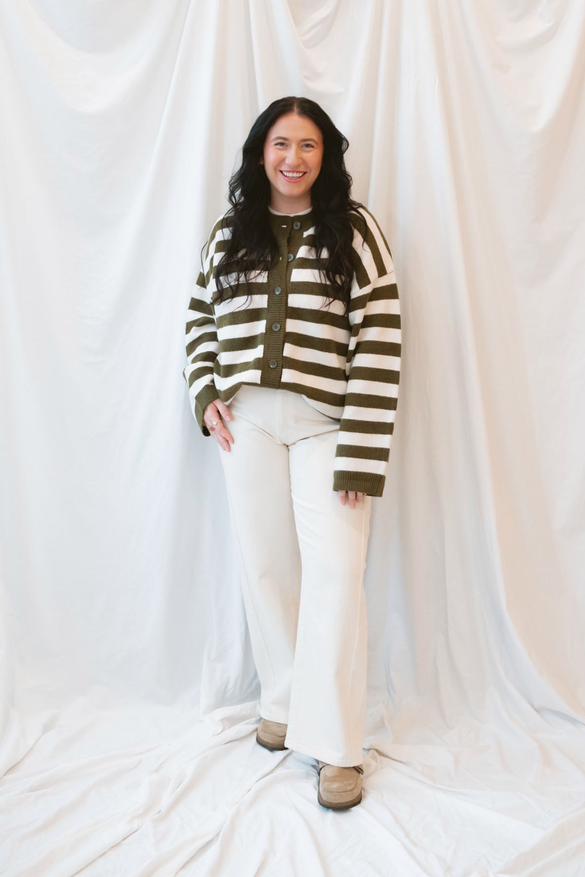 Model is wearing oversized striped button down cardigan in olive and cream.