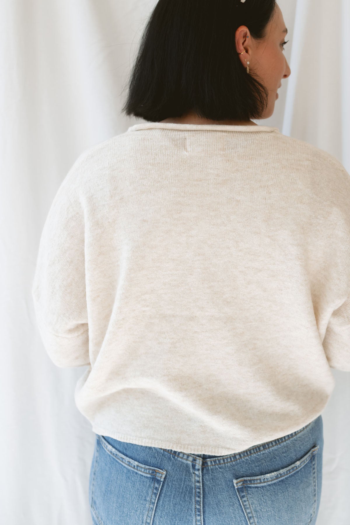 Back view of model wearing button up cardigan in color oat. This cardigan is easy to wear open and layered over a variety of tanks and shirts or you can wear it buttoned up as a top.