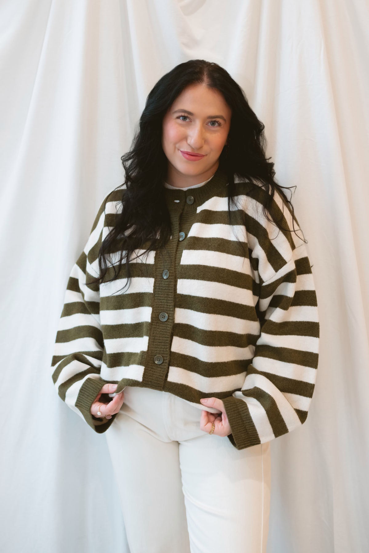 Model is wearing oversized striped button down cardigan in olive and cream.