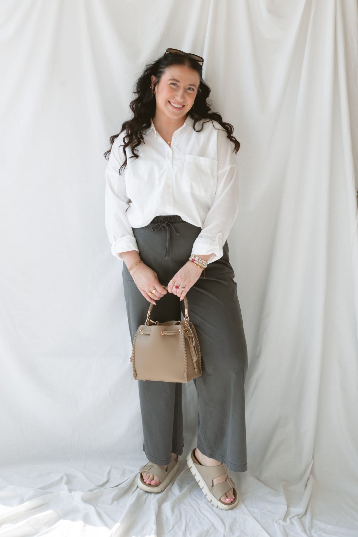 Model wearing the long sleeve white button up top. Model has shirt styled fully buttoned and tucked into the Mila wide leg pants. This outfit is easy and casual but still feels put together.