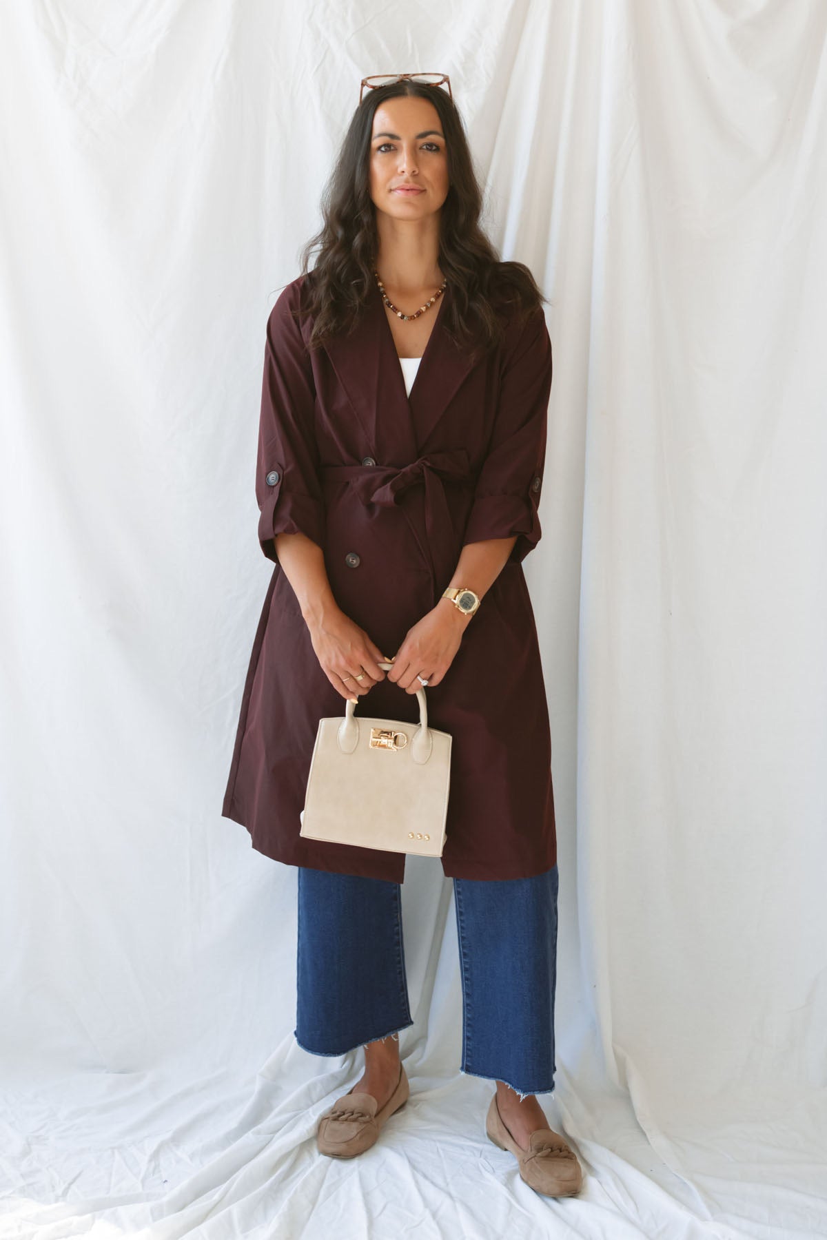 Model wearing the maroon tie waist detail trench coat fully buttoned and tied around the waist.