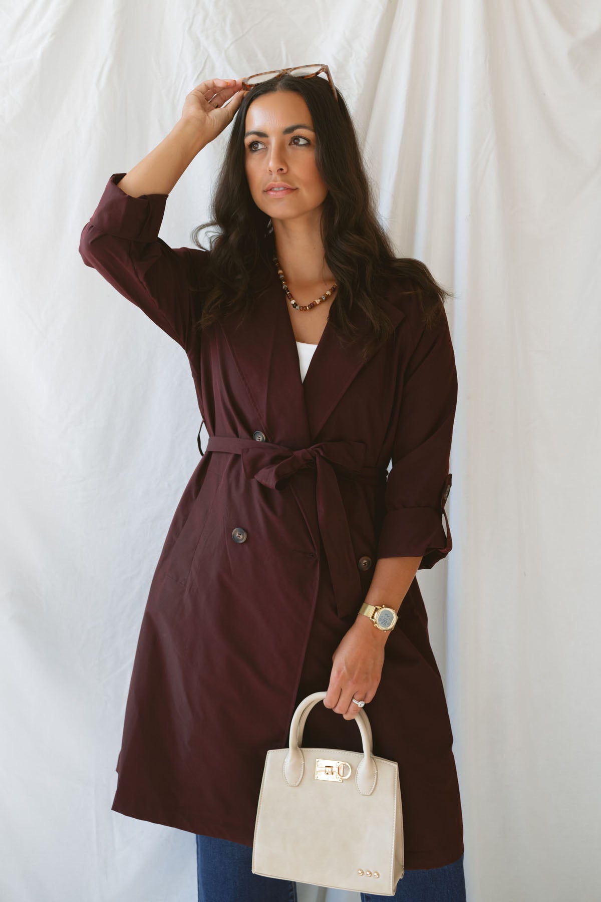 Model wearing the maroon tie waist detail trench coat fully buttoned and tied around the waist.