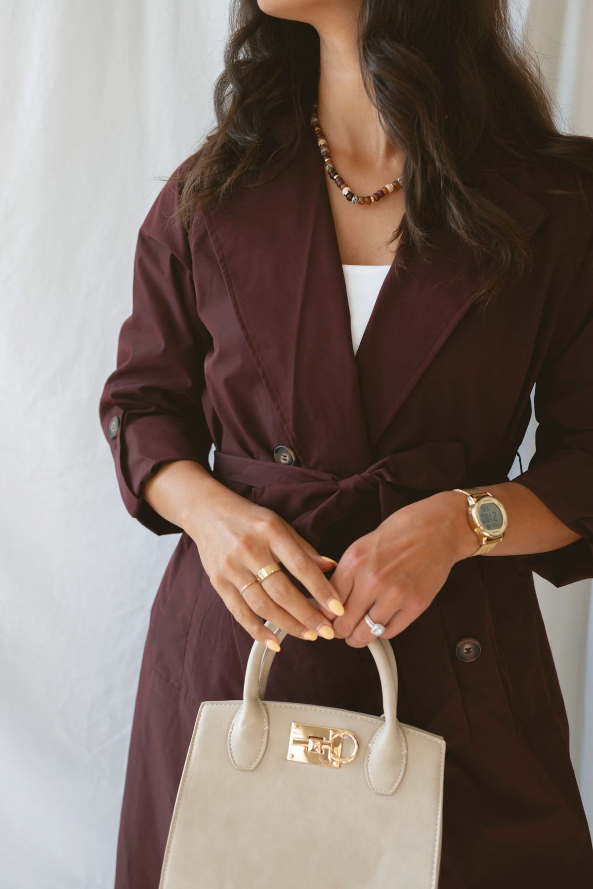Model wearing the maroon tie waist detail trench coat fully buttoned and tied around the waist.