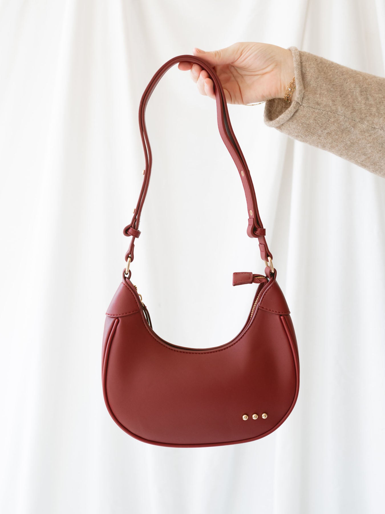 Model holding crescent shaped bag, so you can see strap and front view of bag.