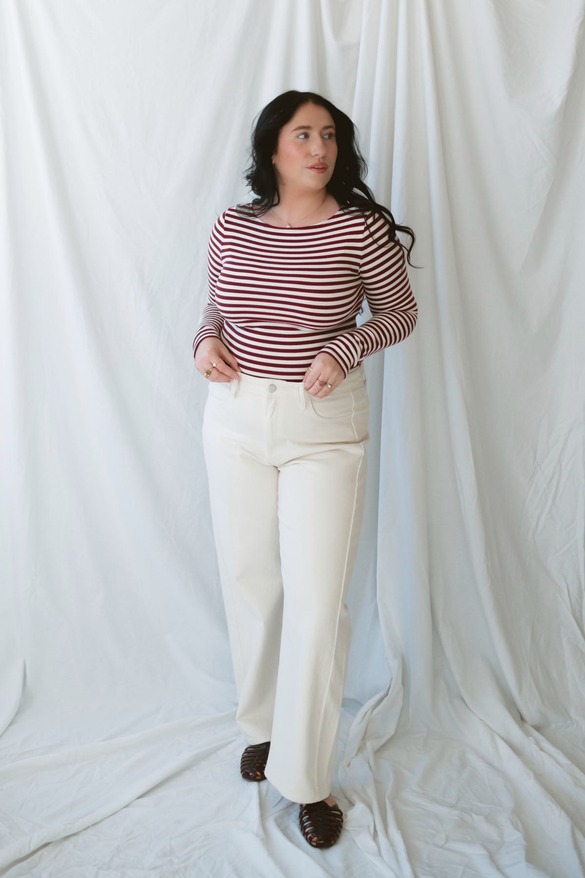 Model wearing long sleeve boat neck style striped top.