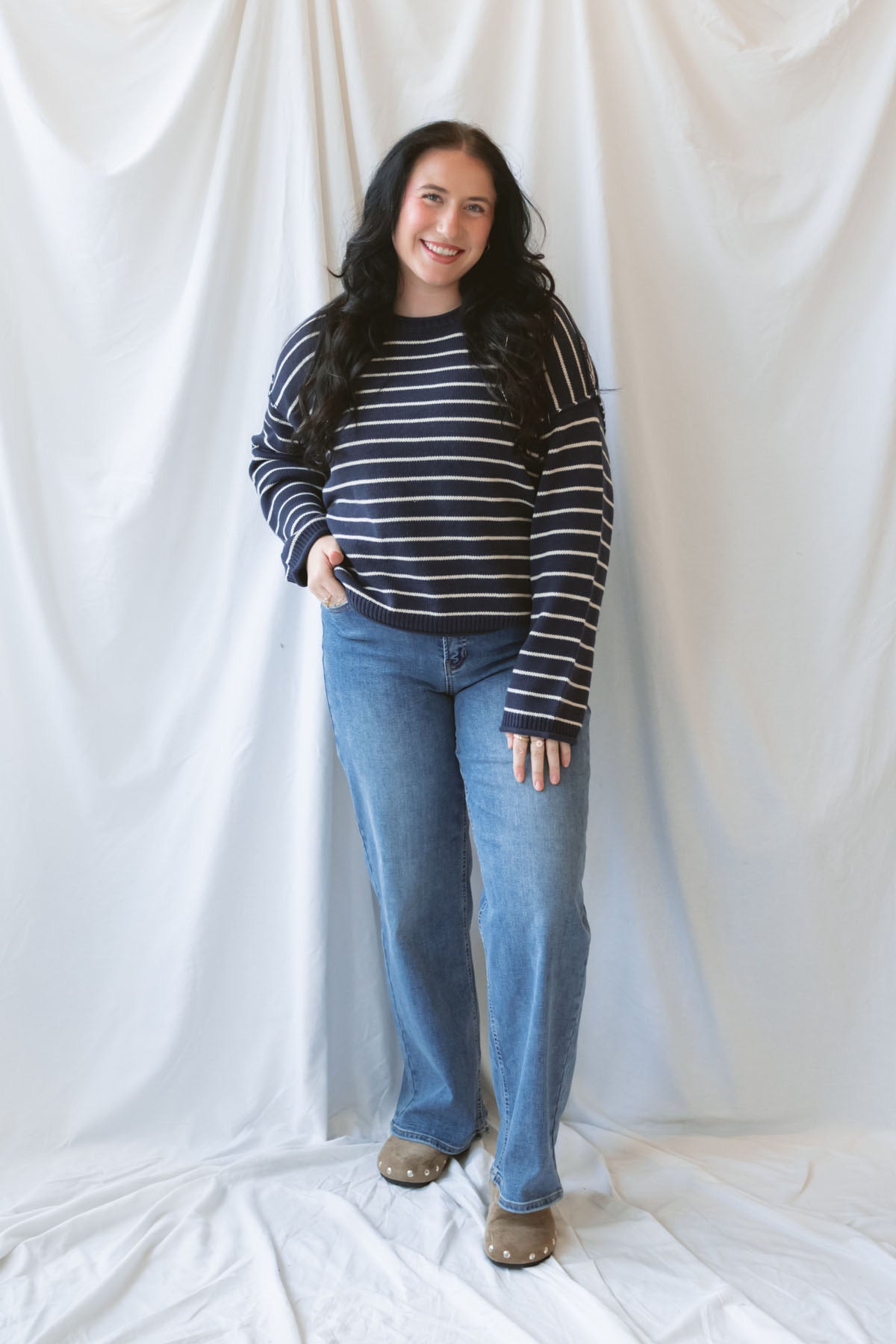Model wearing striped crew neck sweater with raw edge detail.