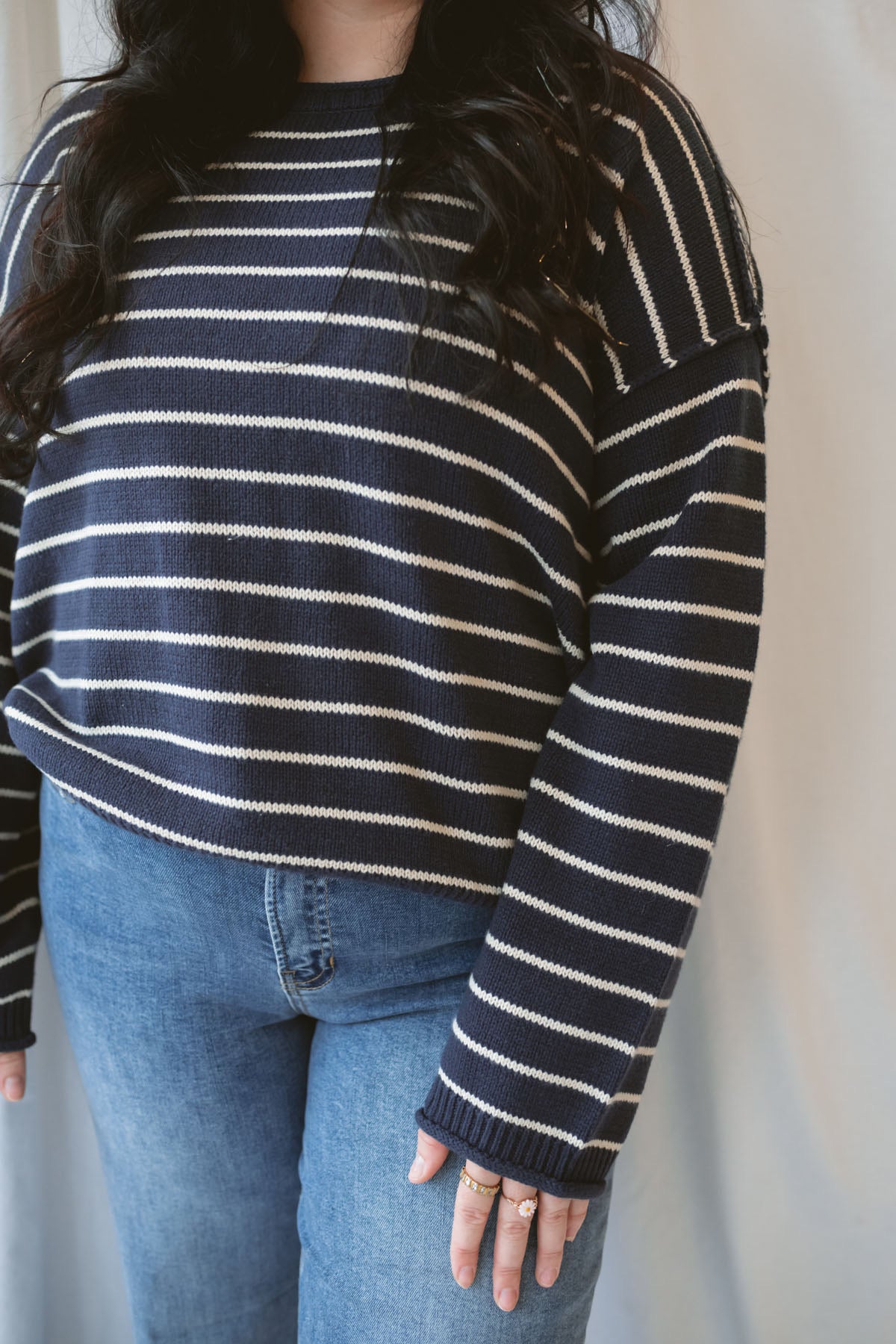 Model wearing striped crew neck sweater with raw edge detail.