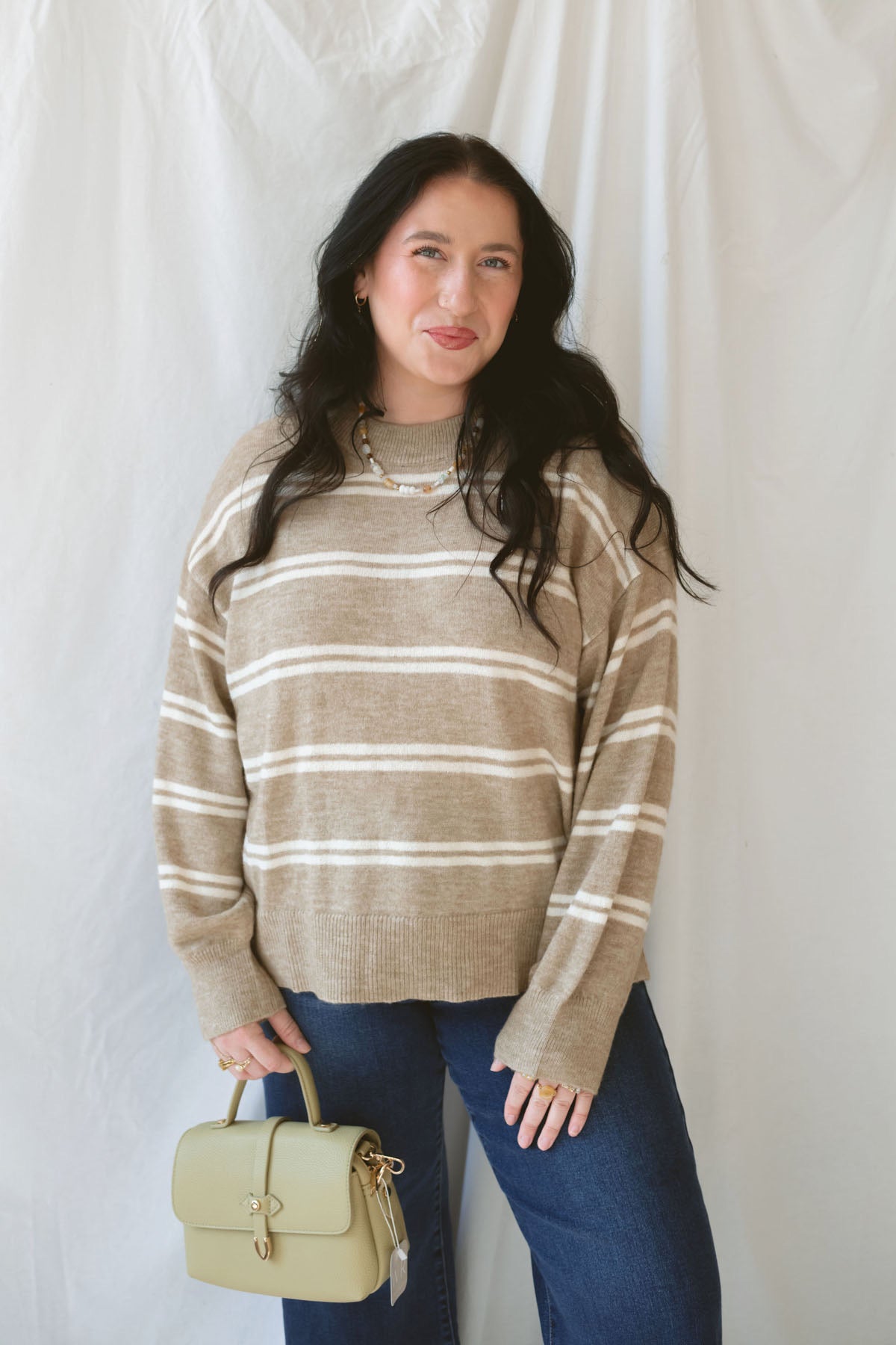 Model wearing the stripe drop sleeve crew neck sweater in mocha. This is perfectly oversized and great to pair with a variety of pants.