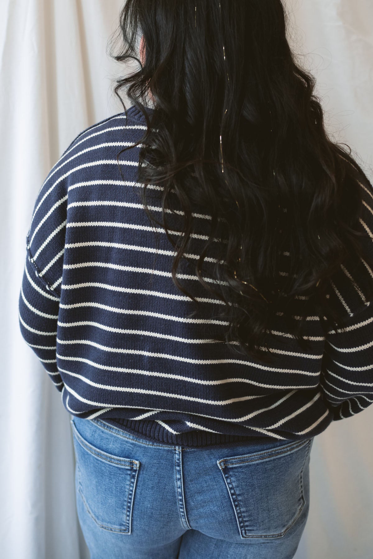 Model wearing striped crew neck sweater with raw edge detail.