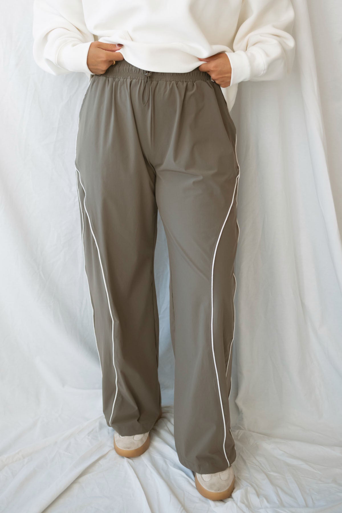 Model wearing the drawstring waist track pants in truffle.