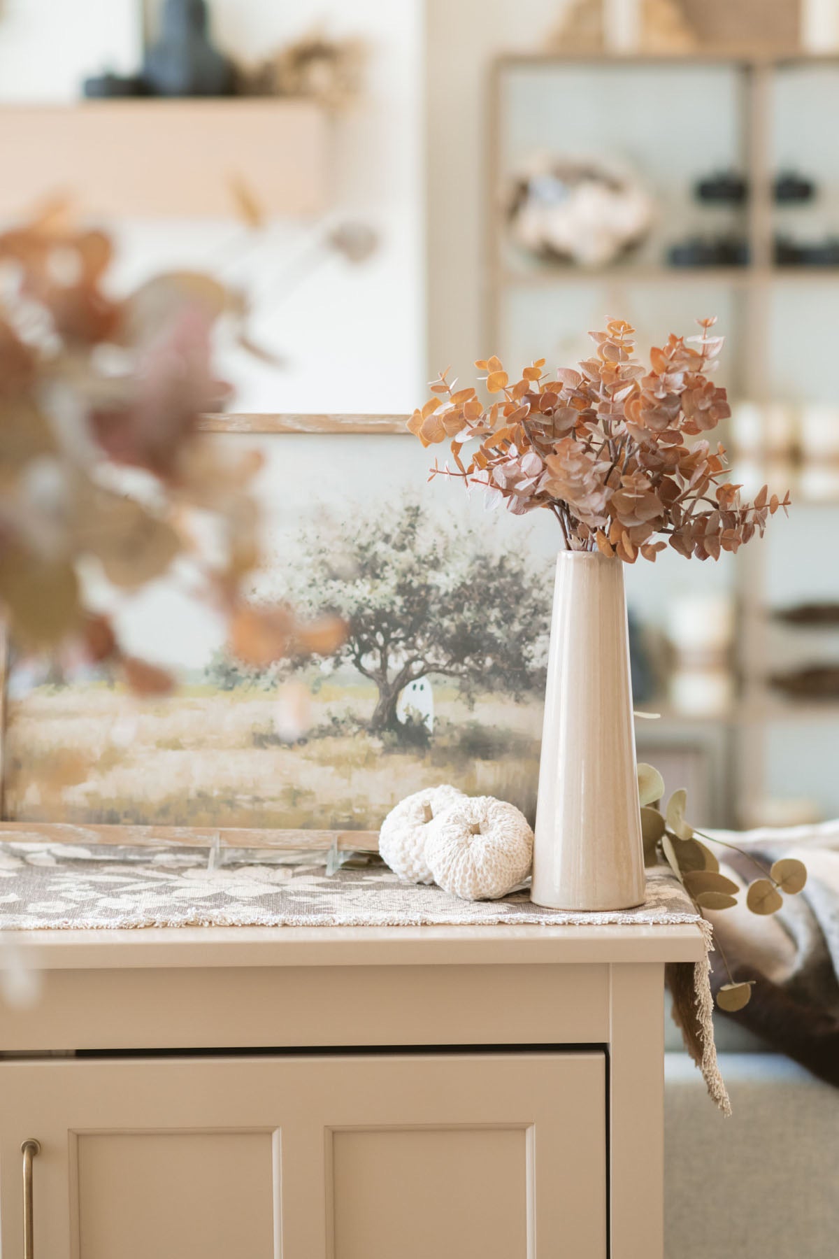 Brown eucalyptus bundle in taupe vase styled on buffet table.