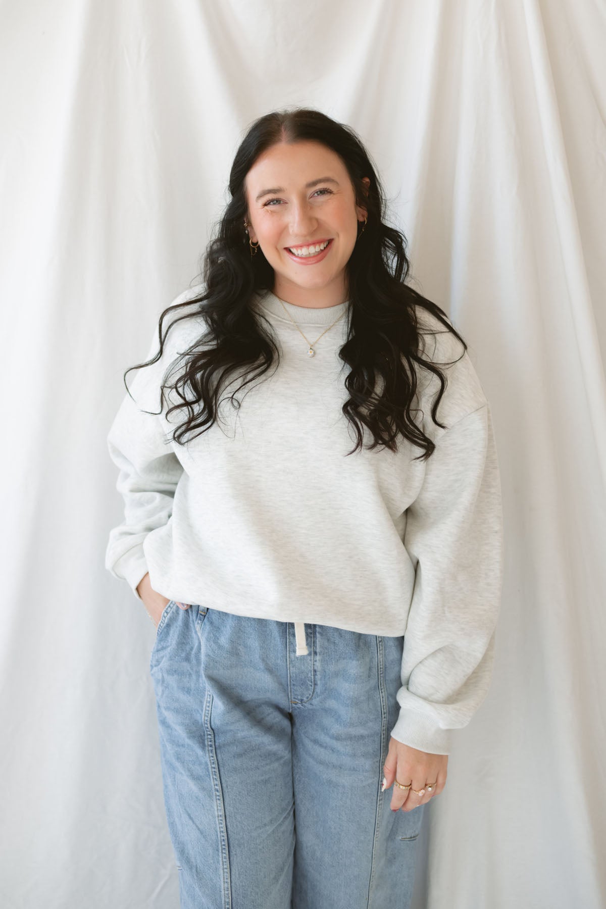 Model wearing the oversized grey crew neck sweatshirt. Model has it styled with a pair of barrel jeans and sneakers for a casual everyday look.