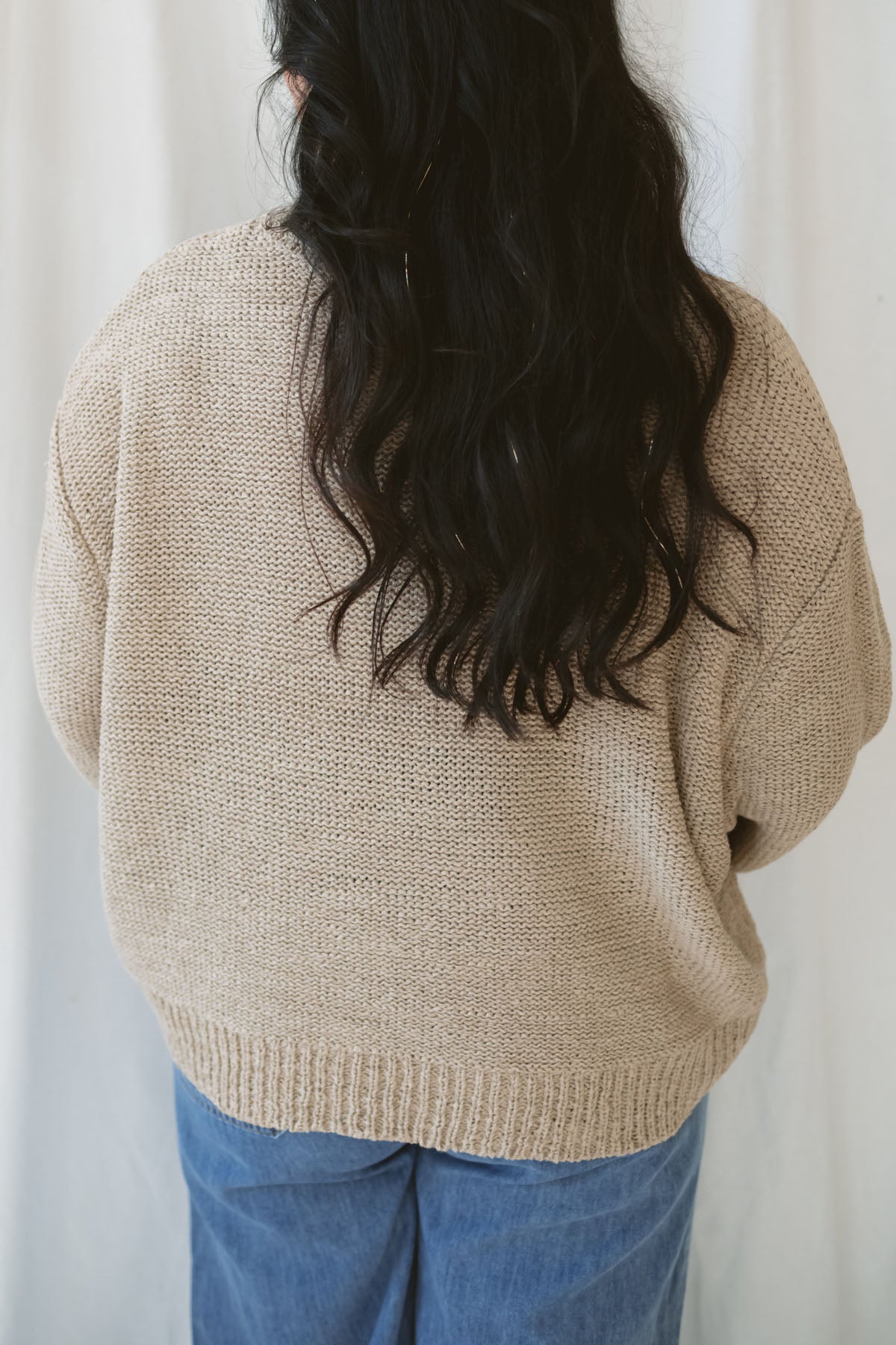 Model is wearing a soft knit round neck sweater with a balloon sleeve.