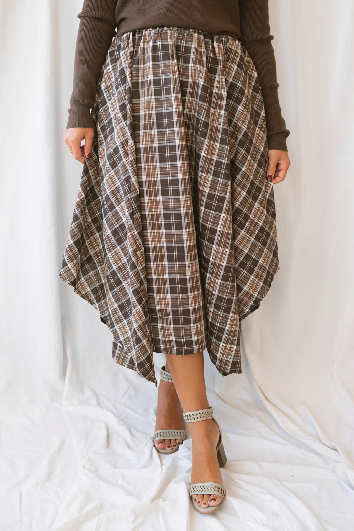 Riley brown plaid midi skirt with an asymmetrical hem and classic autumn pattern.