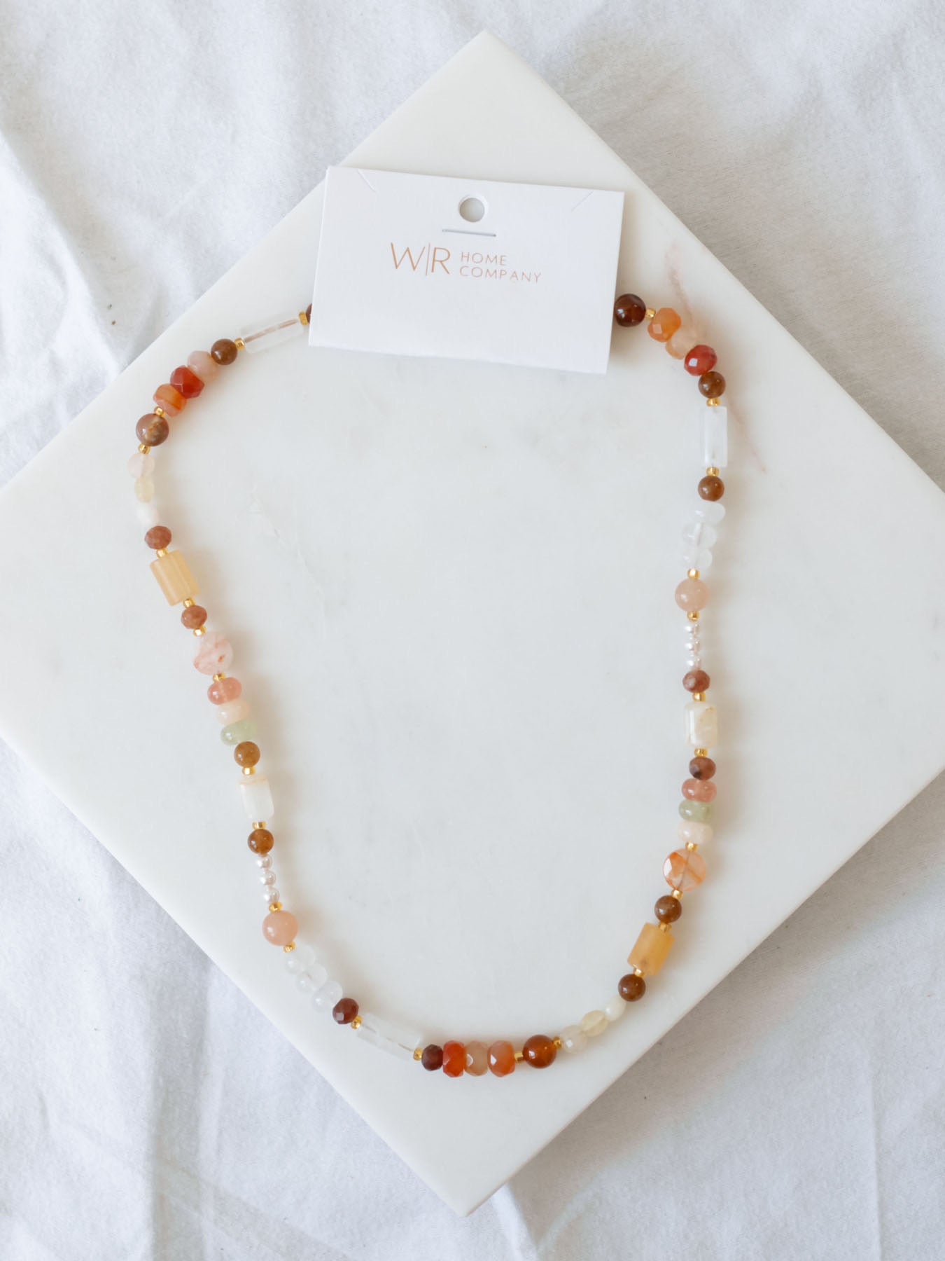 Handmade beaded necklace laying on marble board.