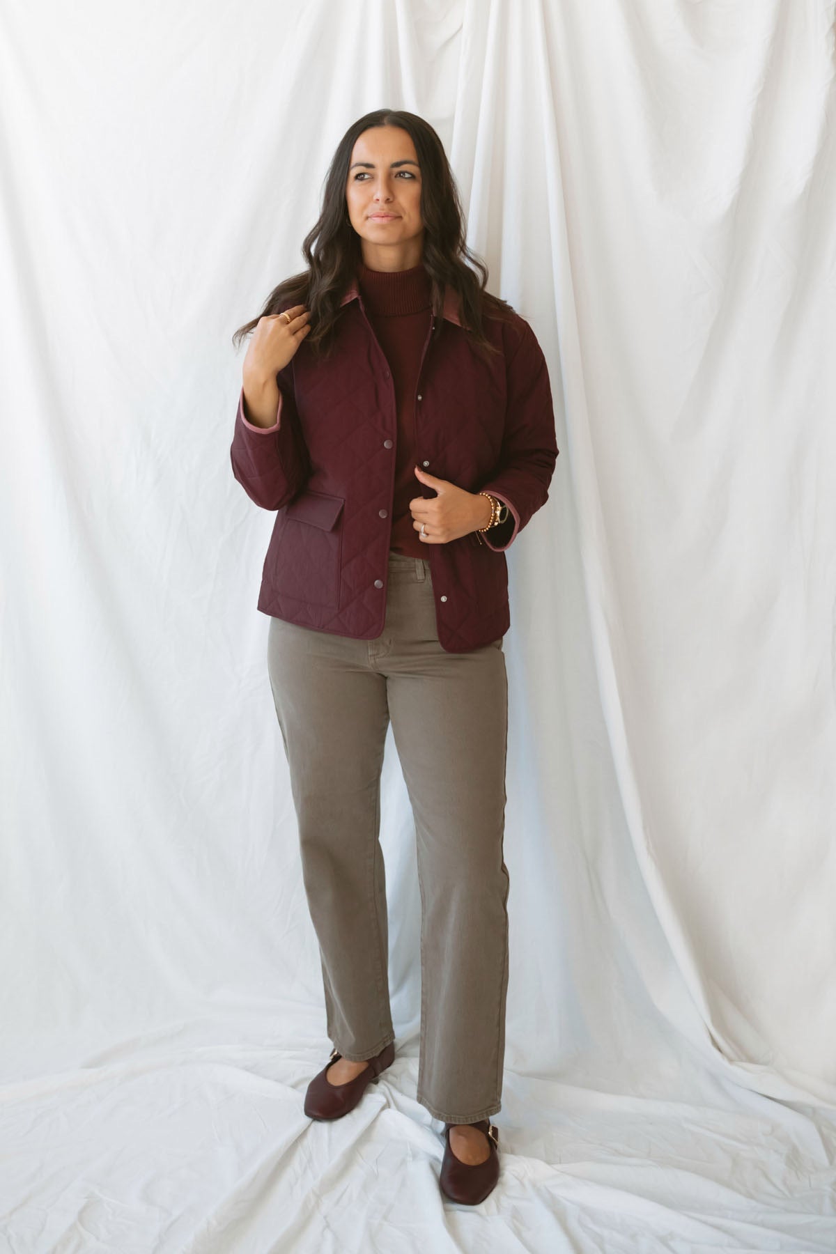 Model is wearing a quilted two tone jacket in burgundy.