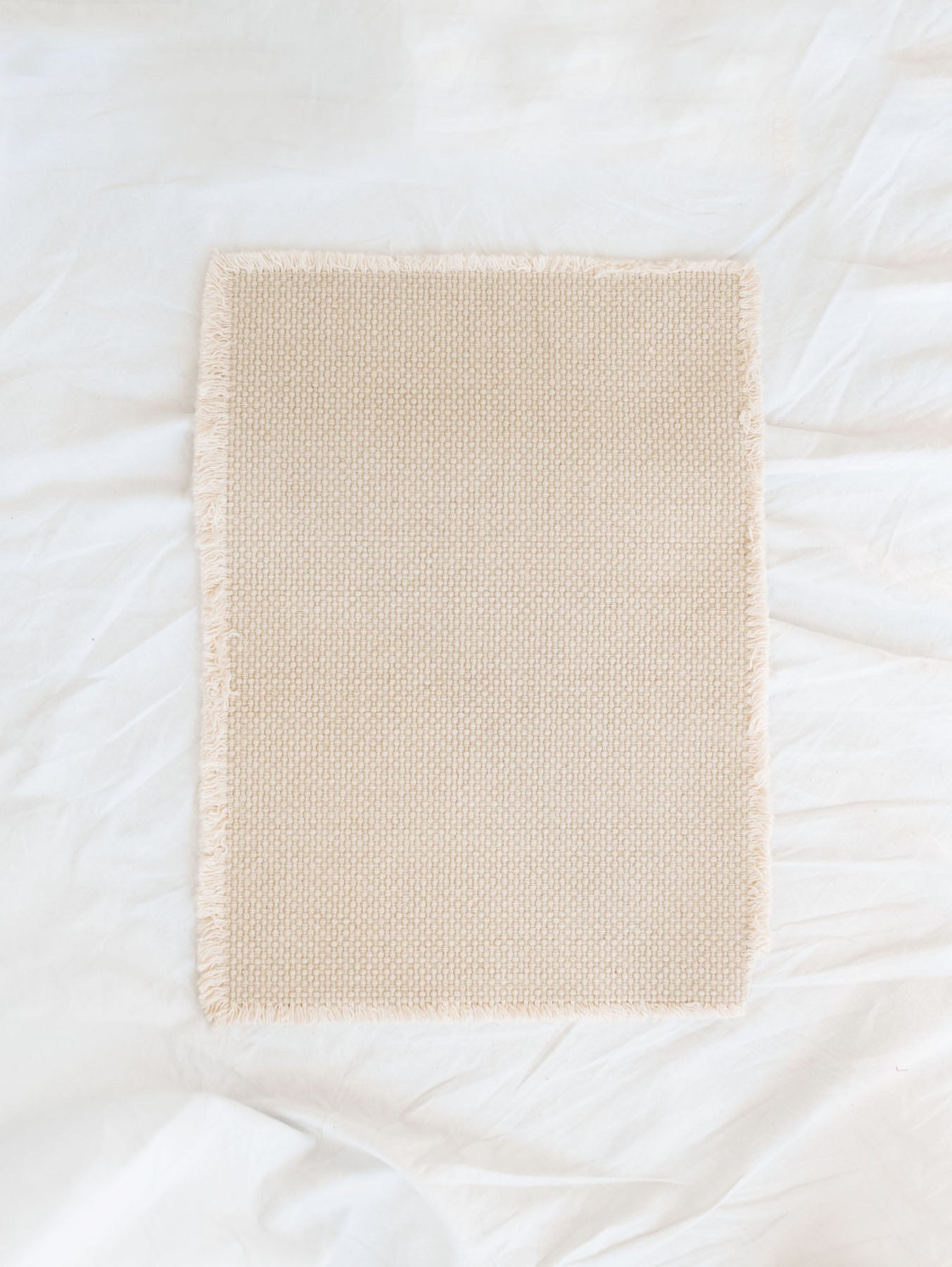 Cotton Beige Placemat with fringe edges laid out on white linen backdrop.