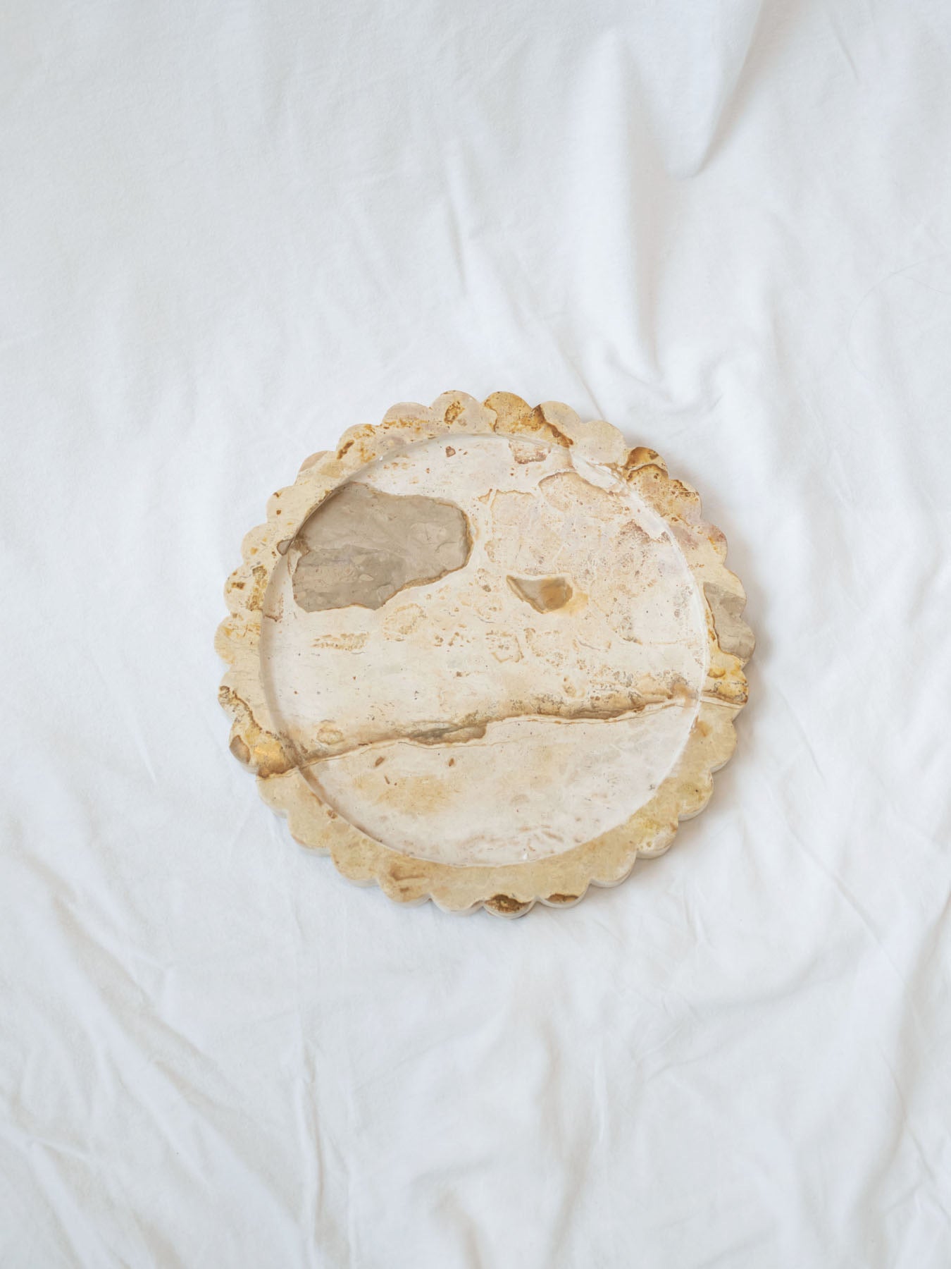 Top view of marble scallop edge tray sitting on white linen backdrop.