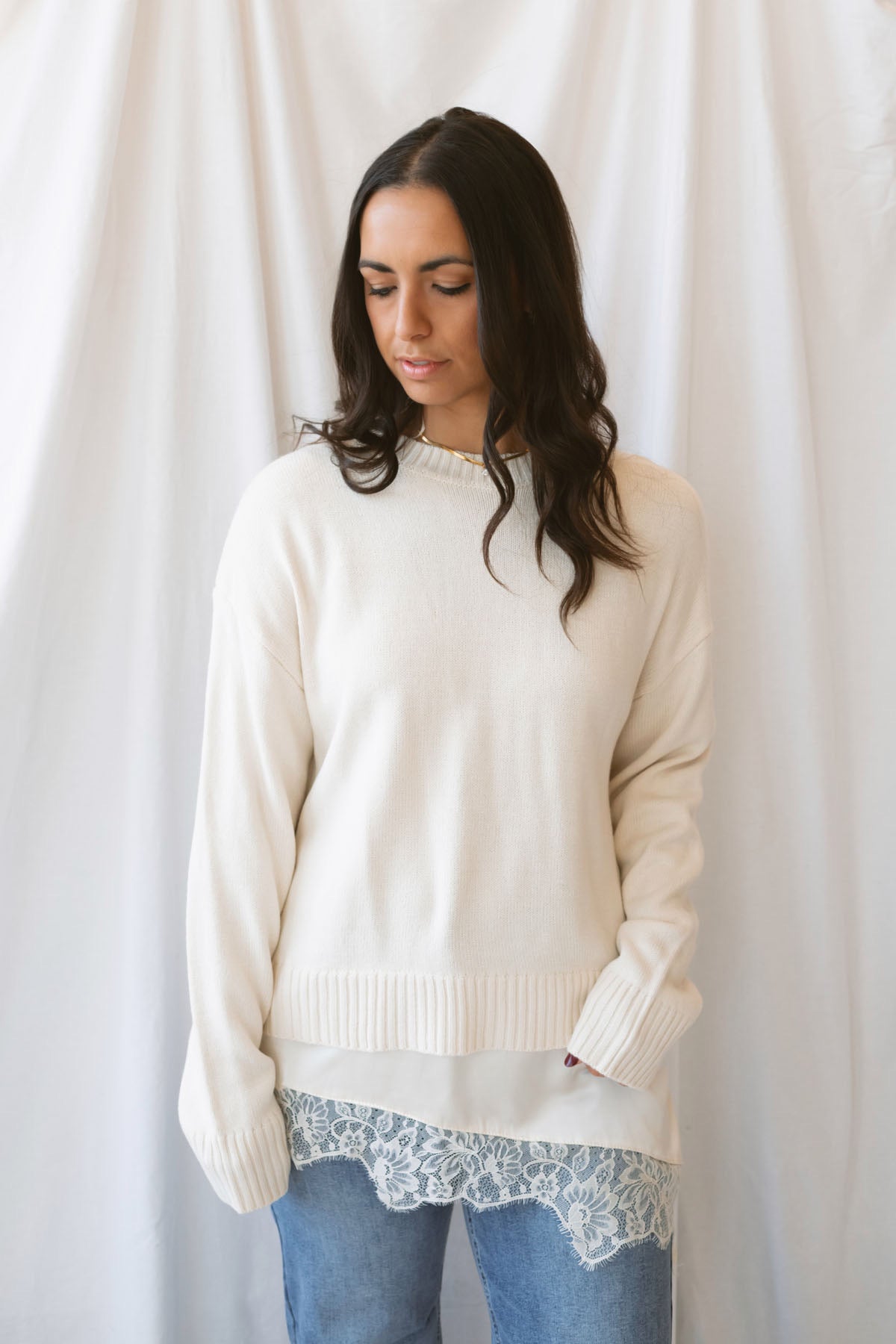 Traci cream knit long sleeve sweater top with a contrasting satin lace layered hem.