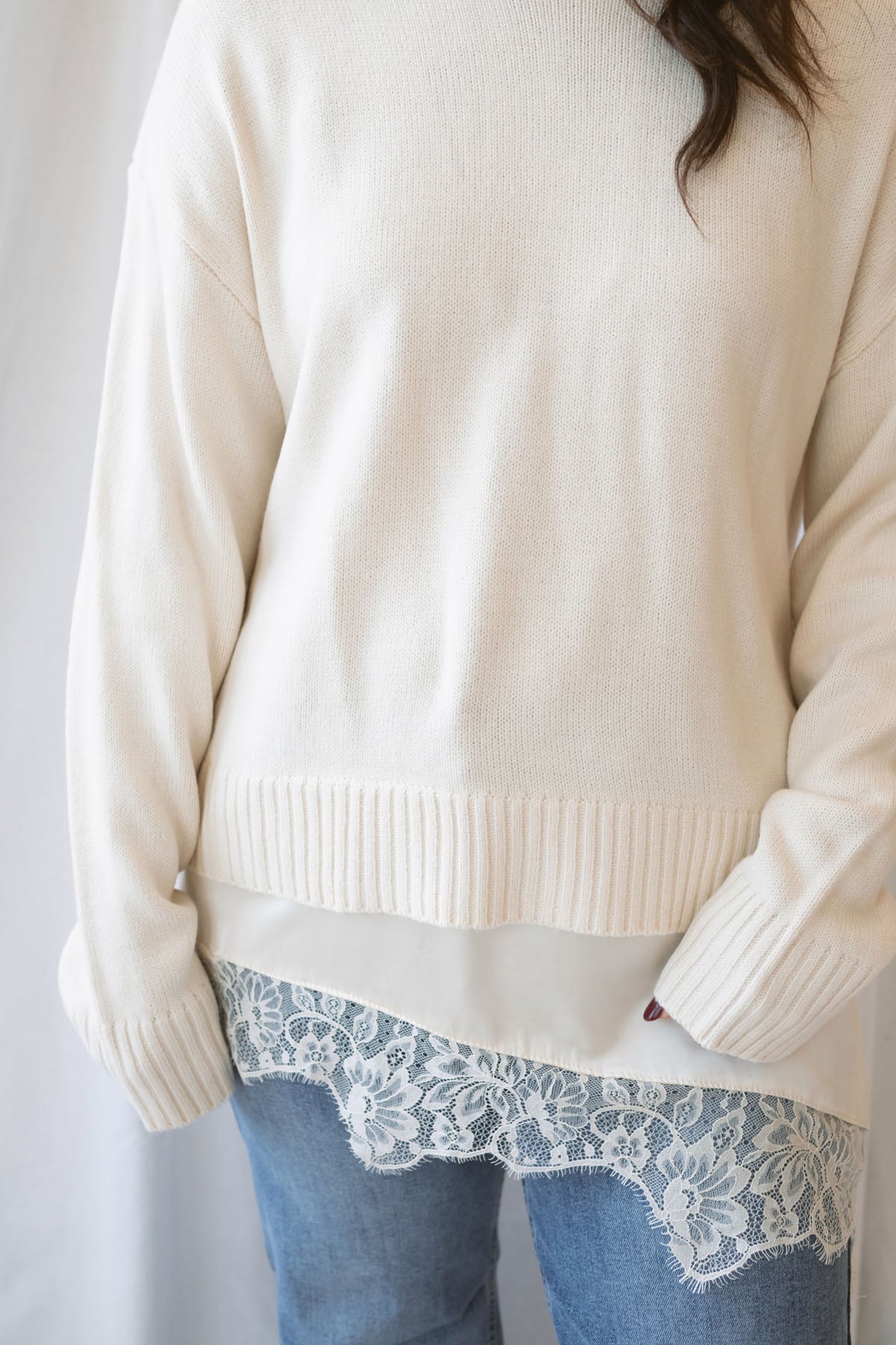 Traci cream knit long sleeve sweater top with a contrasting satin lace layered hem.