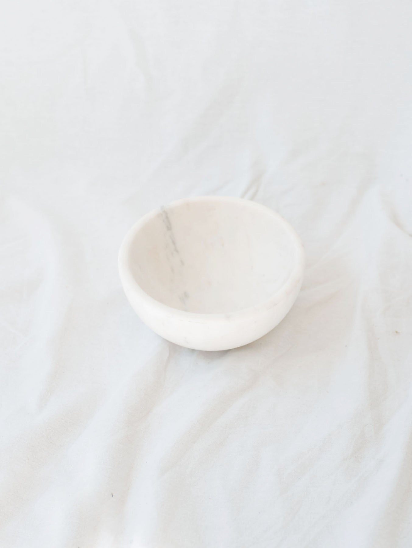 Small size of the marble bowls sitting in front of a white linen backdrop.