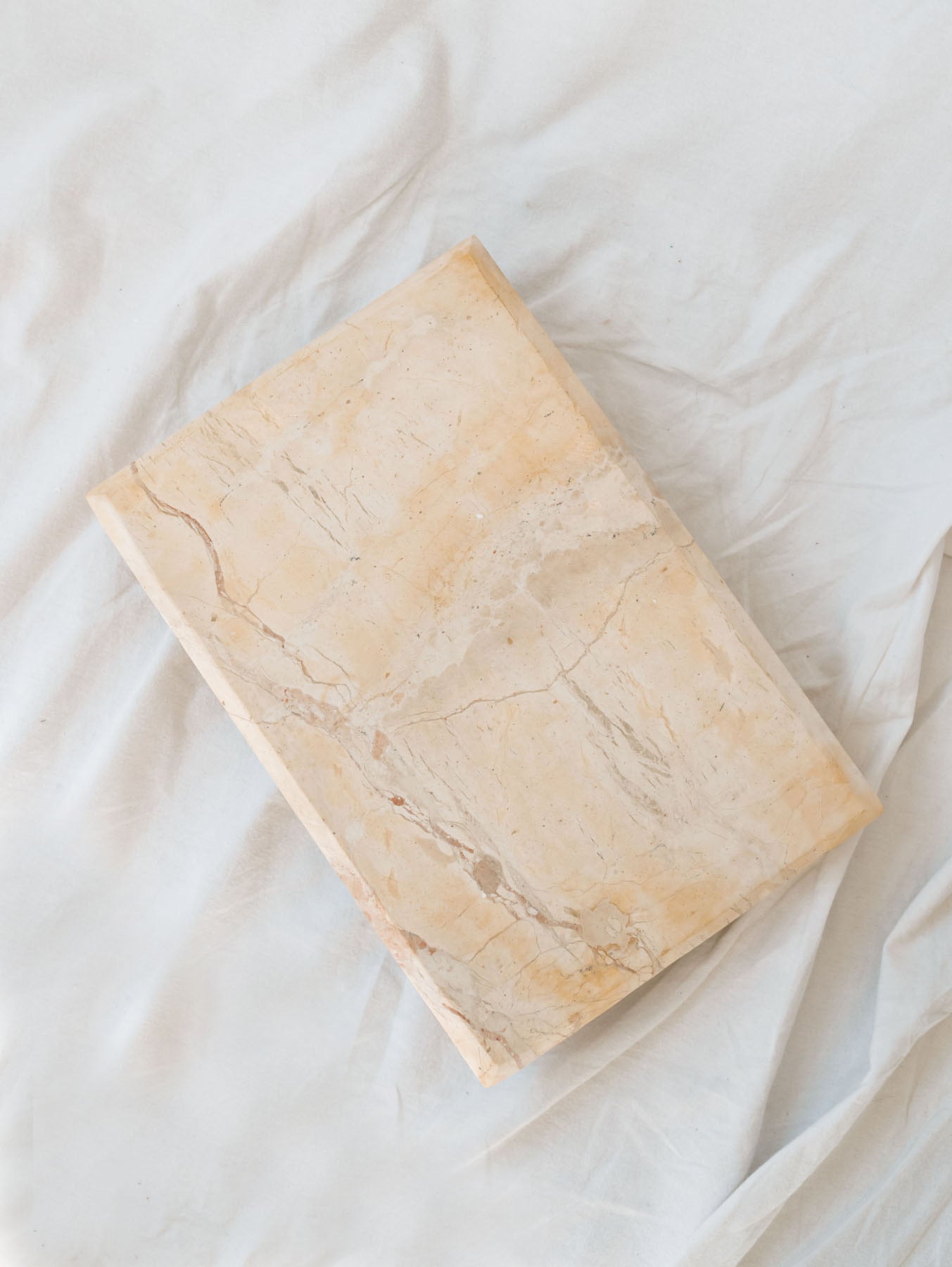 Top view of marble footed decorative riser sitting on white linen backdrop.