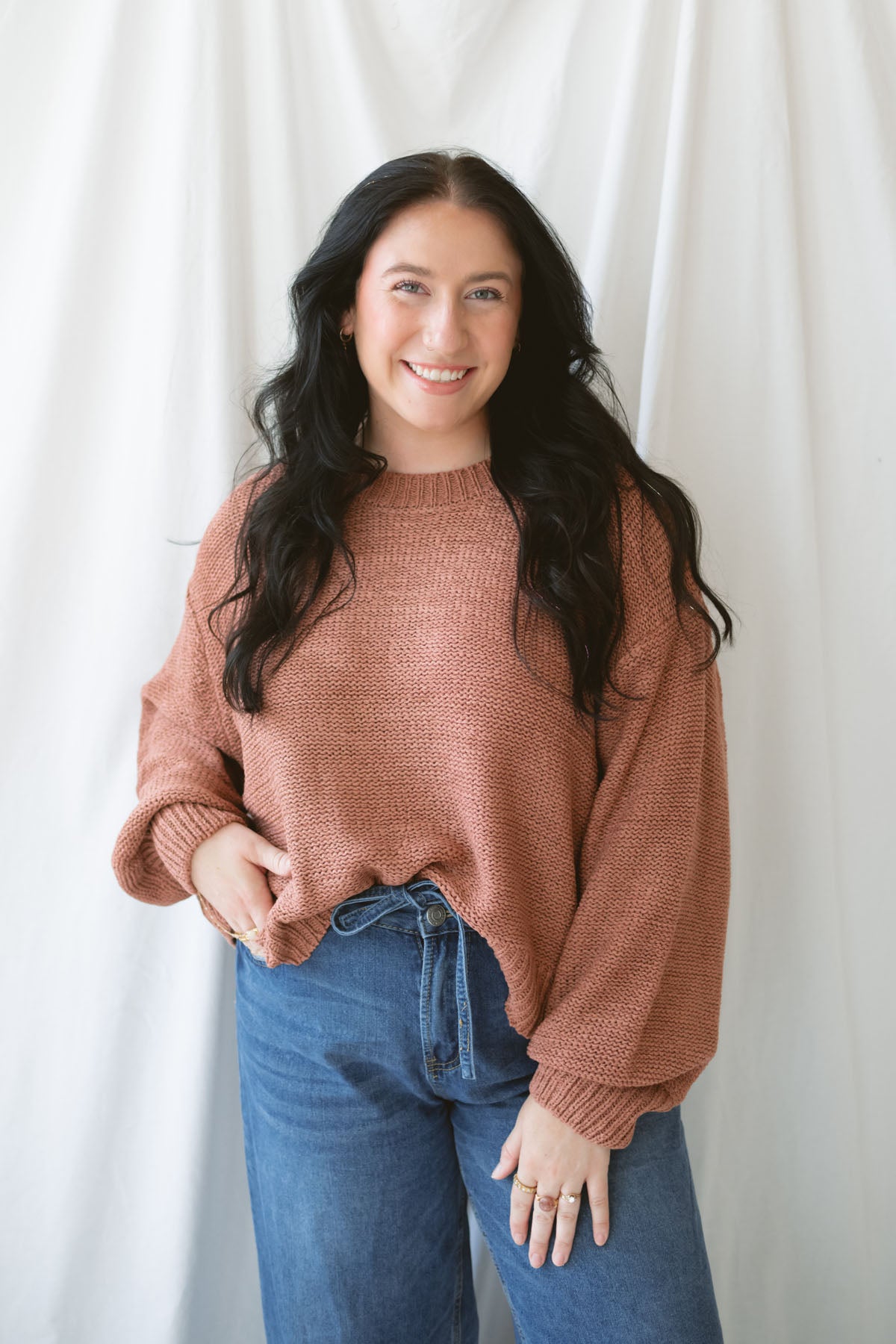 Model is wearing a round neck knit sweater featuring balloon sleeves
