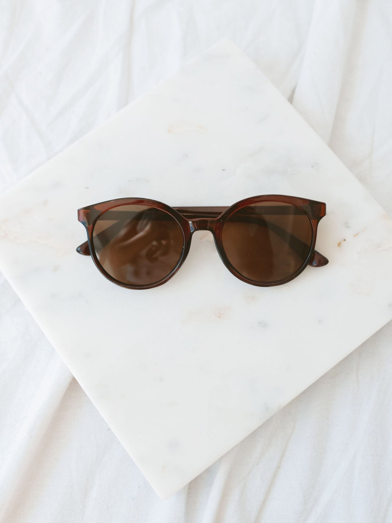 Tortoise round lens sunglasses laying on marble board.
