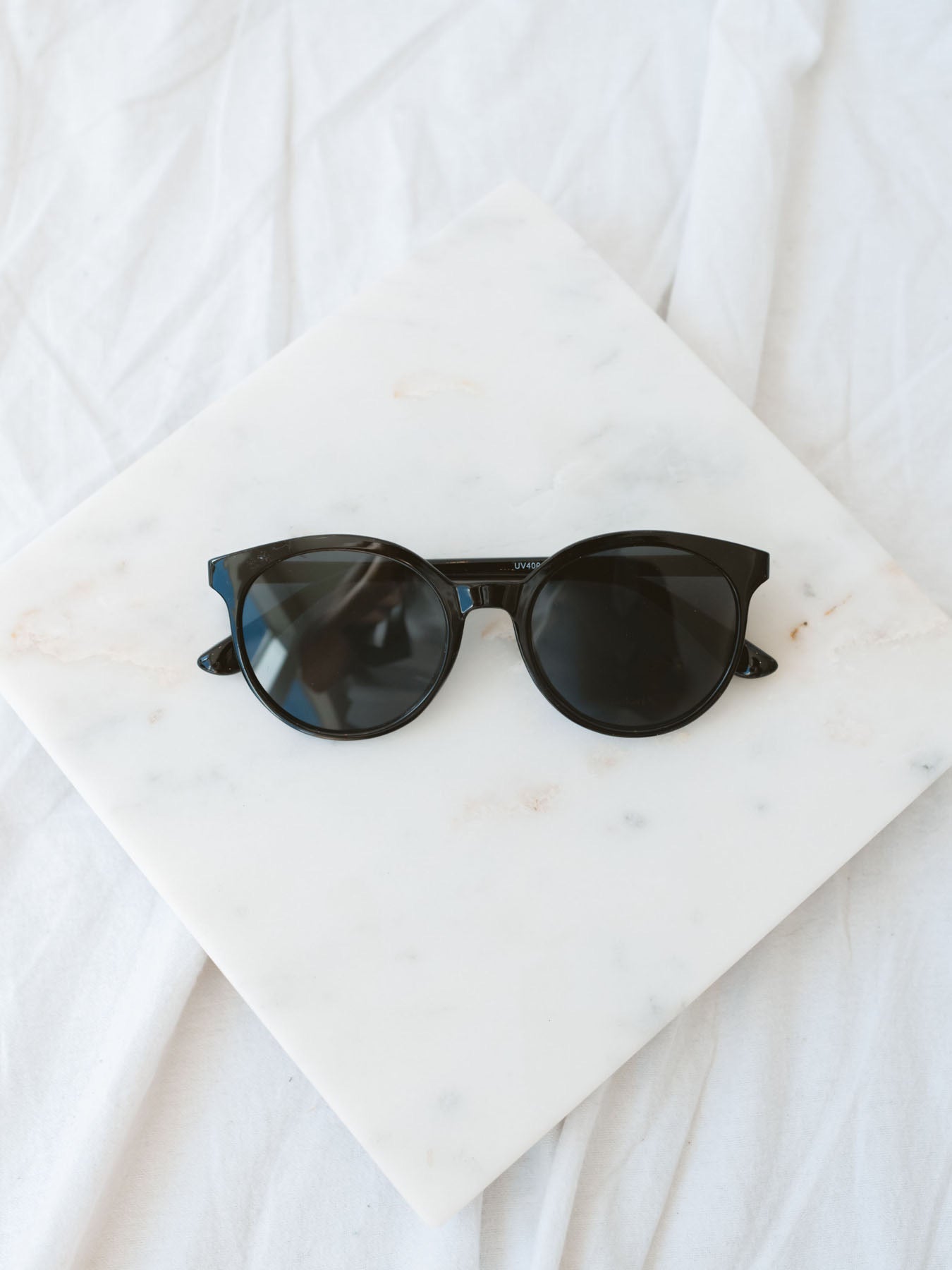 Black round lens sunglasses laying on marble board.