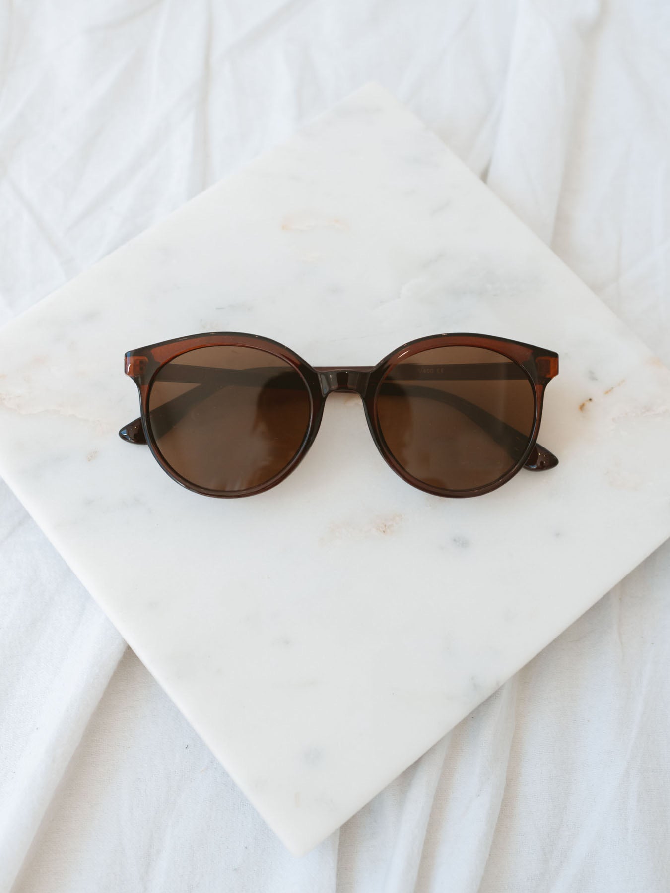 Brown round lens sunglasses laying on marble board.