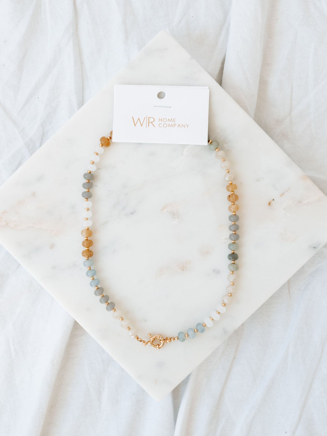 Round beaded necklace laying on marble board.