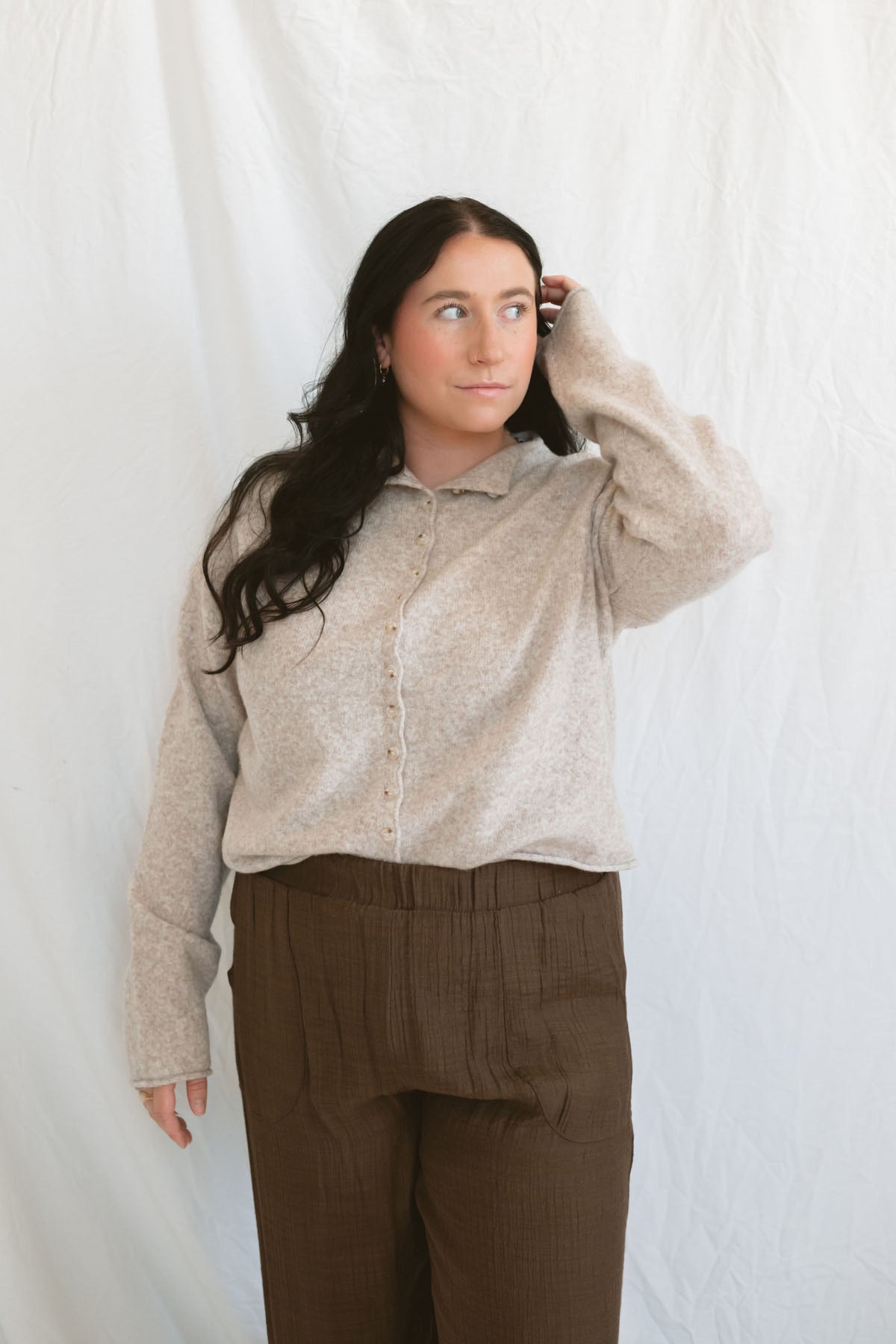 Model wearing full button up mock neck cardigan in oat.