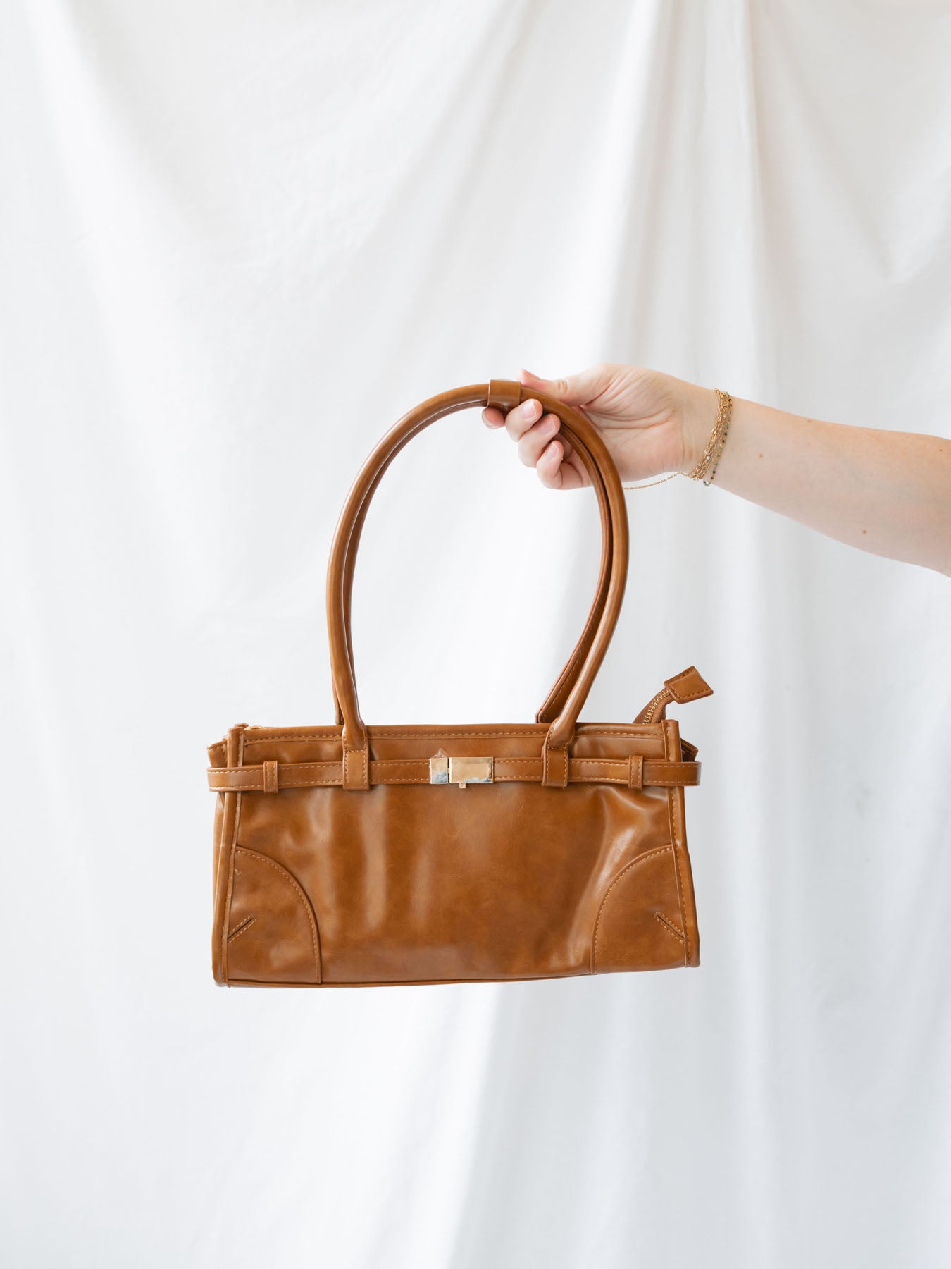 Model holding vintage inspired vegan leather purse with oversized shoulder straps.