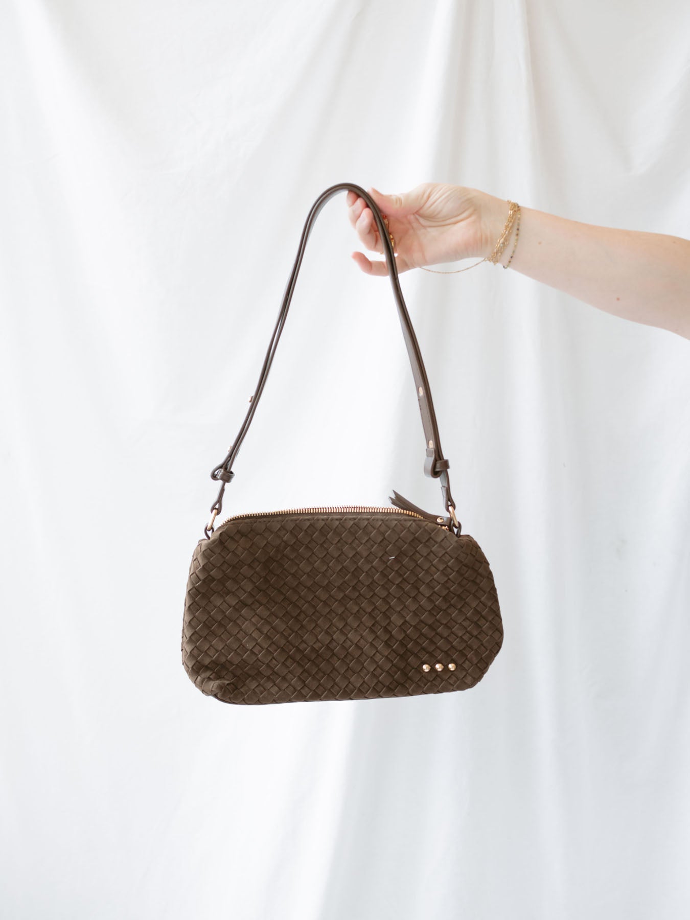 Model holding woven slouch bag with adjustable shoulder strap.